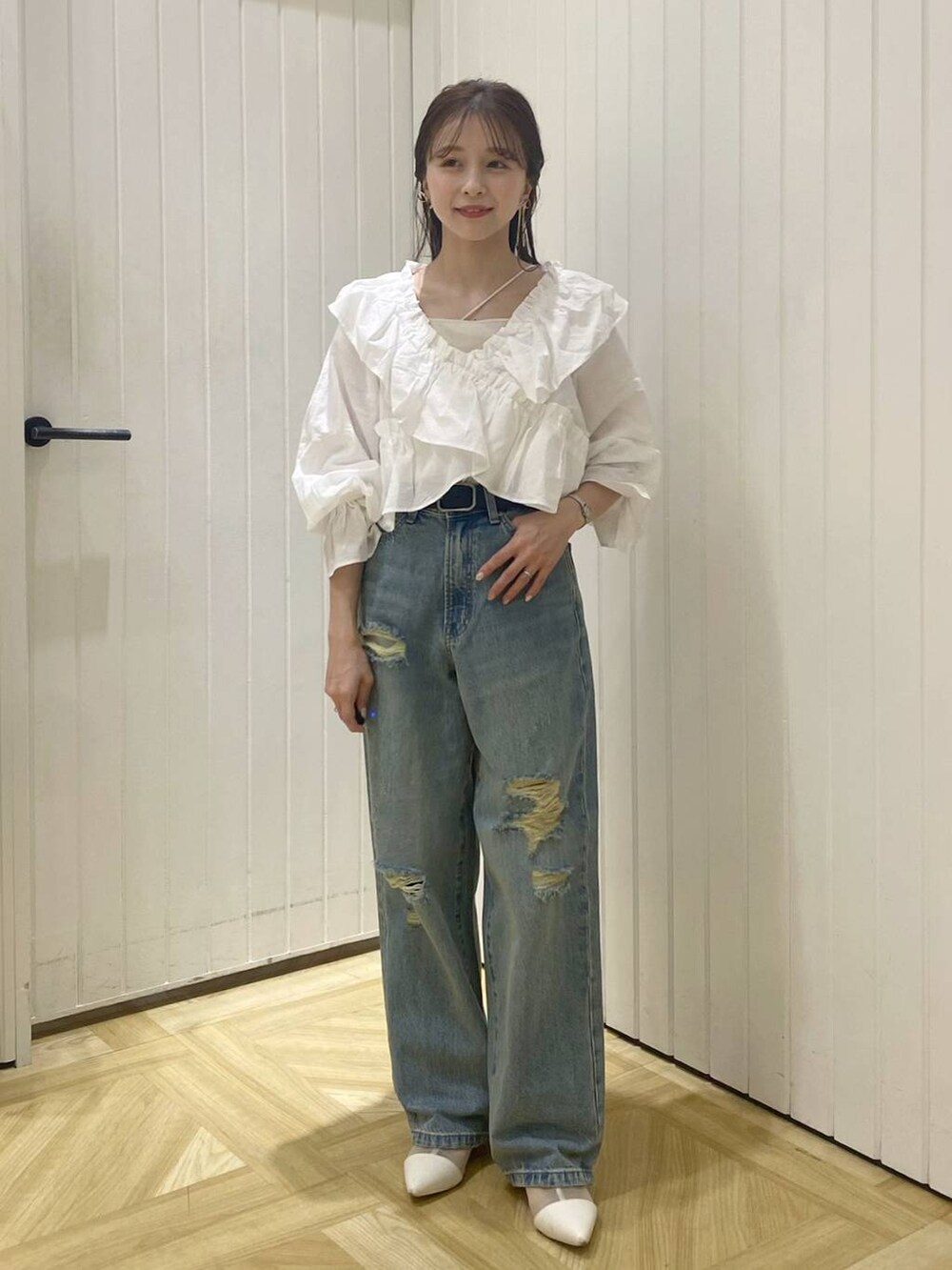 ホワイト系のブーツ、ブルー系のデニムパンツ、ホワイト系のキャミソールを着用したレディースの春コーディネートの2枚目の写真