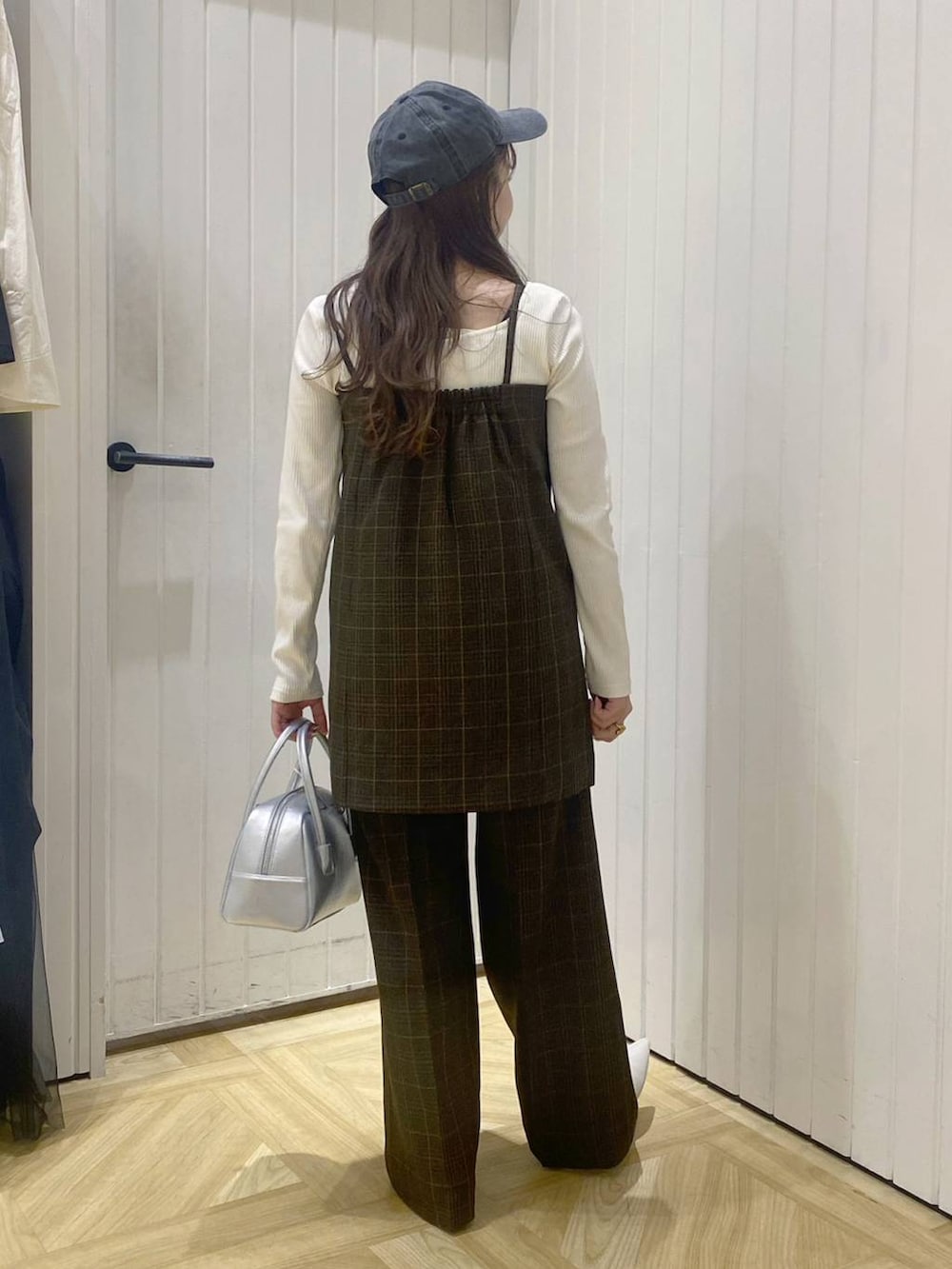 ブラウン系のスラックス、ブラウン系のベスト、シルバー系のボストンバッグを着用したレディースの秋コーディネートの3枚目の写真