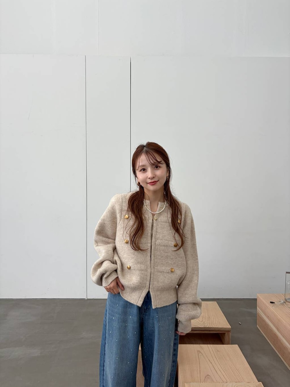 ブラウン系のブーツ、ブルー系のデニムパンツ、ホワイト系のノーカラージャケットを着用したレディースの秋コーディネートの2枚目の写真