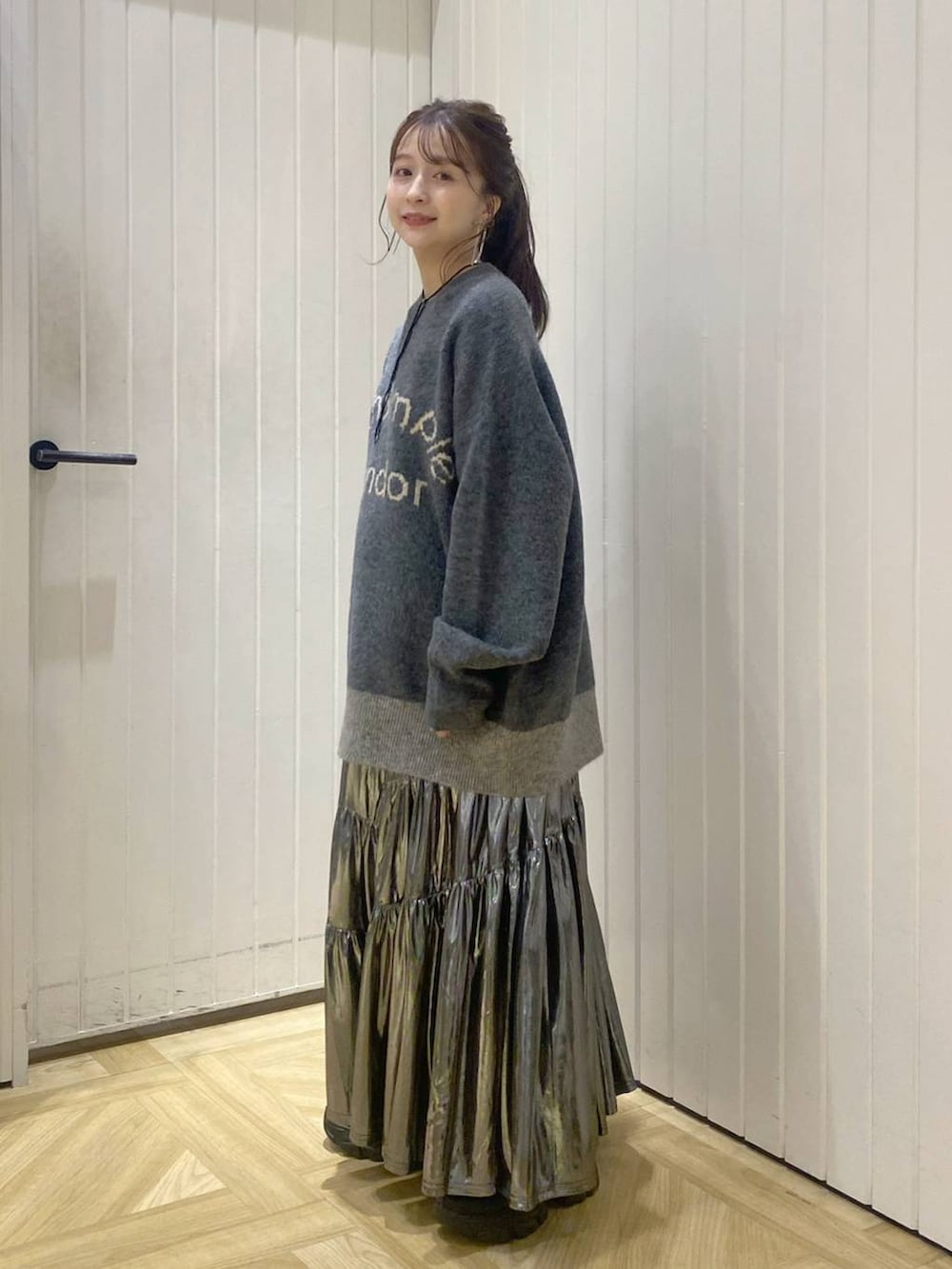 ブラック系のブーツ、ホワイト系のスカート、グレー系のニット/セーターを着用したレディースの秋コーディネートの2枚目の写真