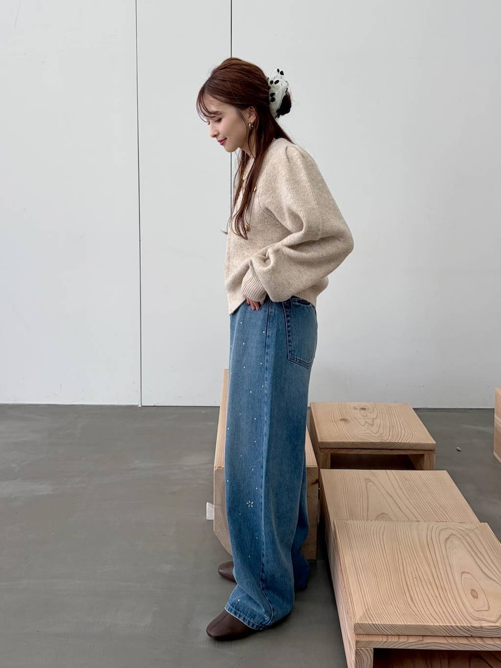 ブラウン系のブーツ、ブルー系のデニムパンツ、ホワイト系のノーカラージャケットを着用したレディースの秋コーディネートの3枚目の写真
