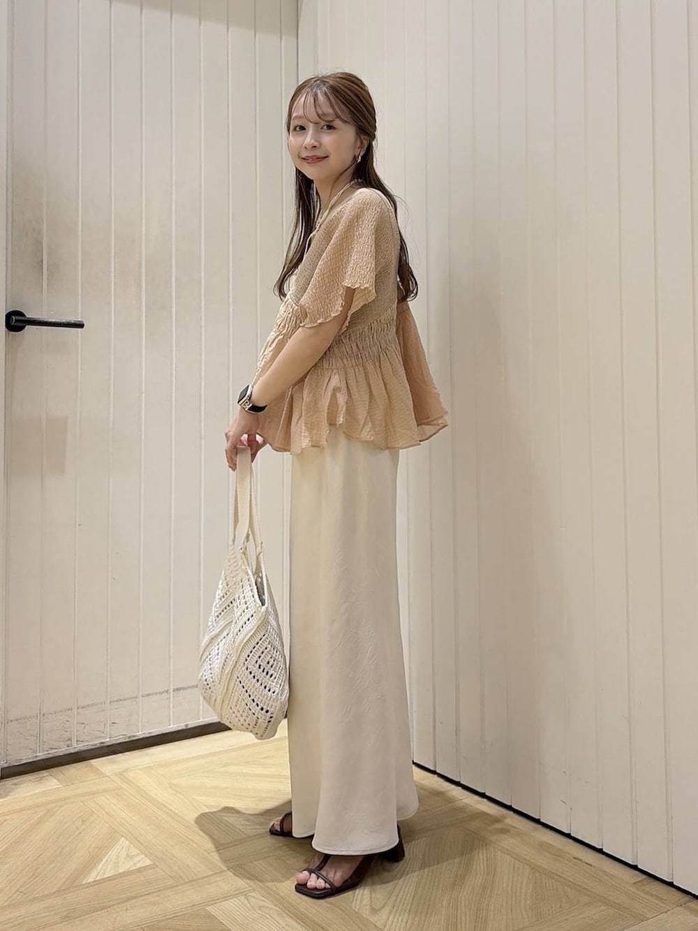 ブラウン系のTシャツ/カットソー、ホワイト系のスカート、ブラウン系のサンダルを着用したレディースの夏コーディネートの2枚目の写真