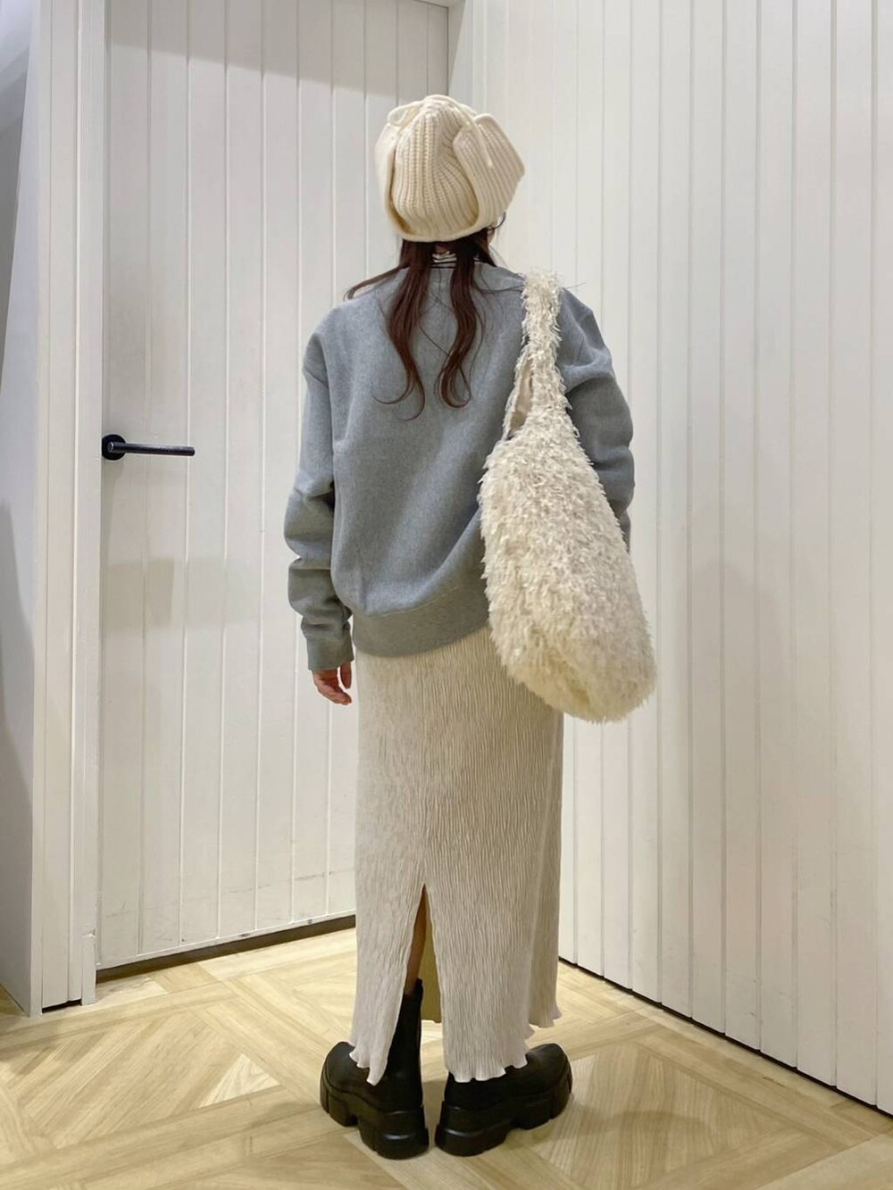 ブラック系のブーツ、グレー系のスウェット、ホワイト系のスカートを着用したレディースの冬コーディネートの3枚目の写真