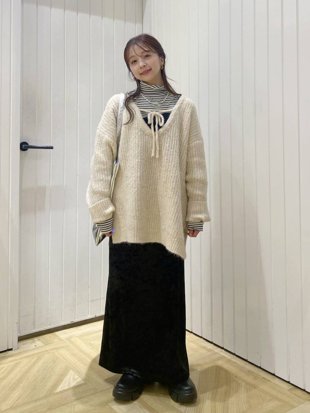 ホワイト系のTシャツ/カットソー、ブラック系のブーツ、シルバー系のトートバッグを着用したレディースの冬コーディネートの2枚目の写真