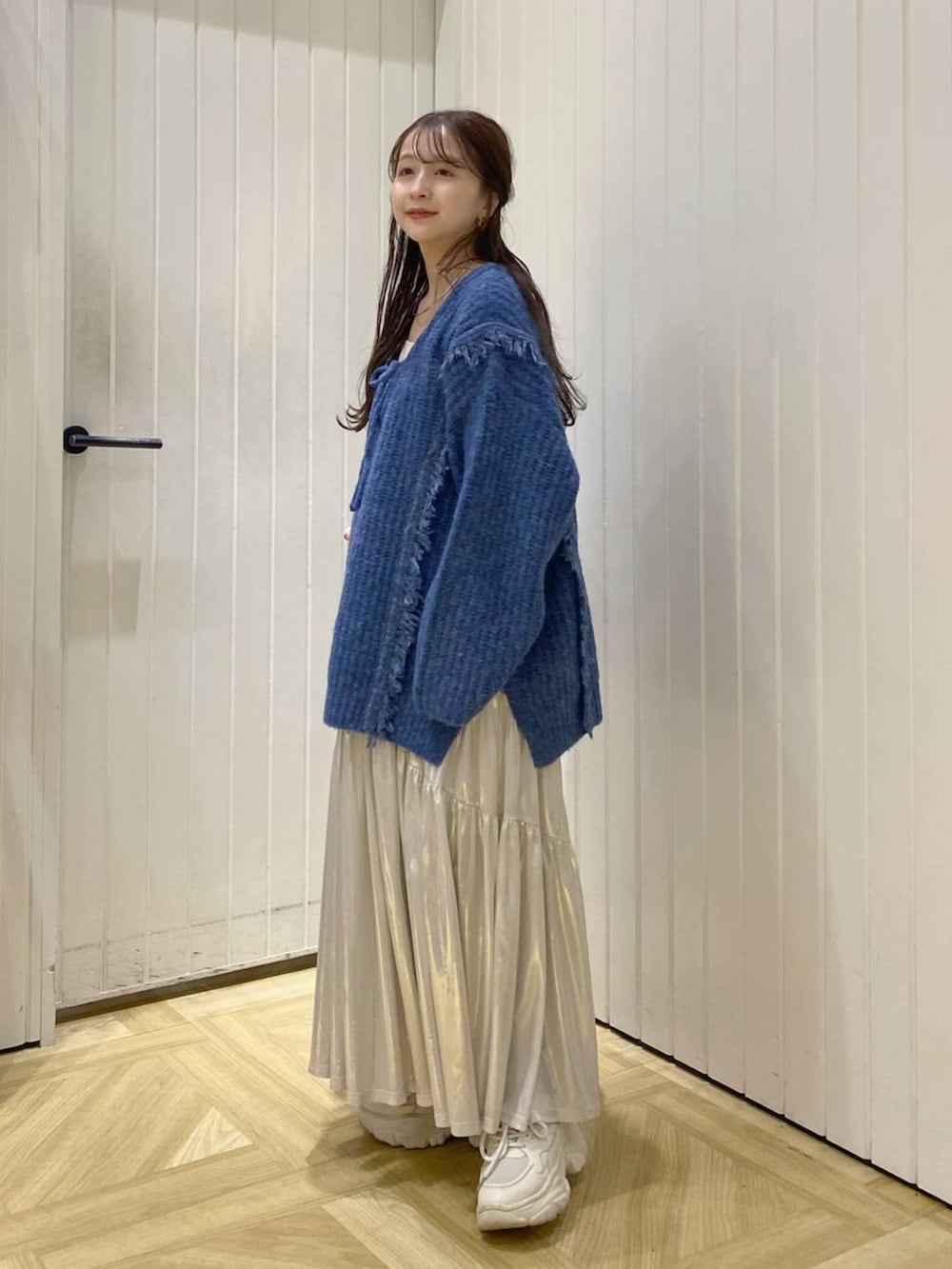 ブルー系のニット/セーター、ホワイト系のタンクトップ、ホワイト系のスニーカーを着用したレディースの秋コーディネートの3枚目の写真