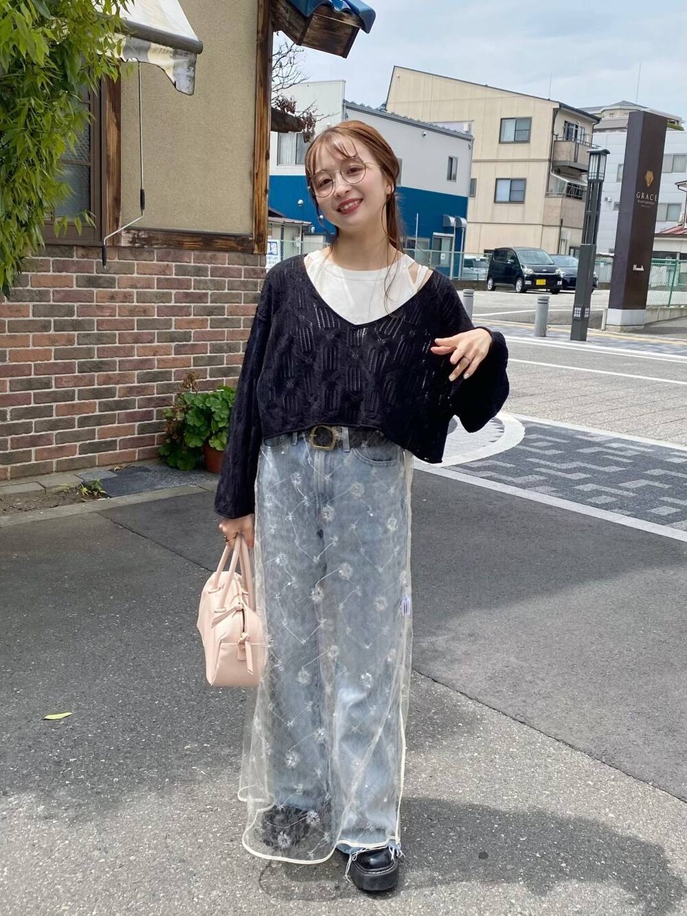 ブラック系のニット/セーター、ブルー系のデニムパンツ、ホワイト系のワンピースを着用したレディースの春コーディネートの3枚目の写真