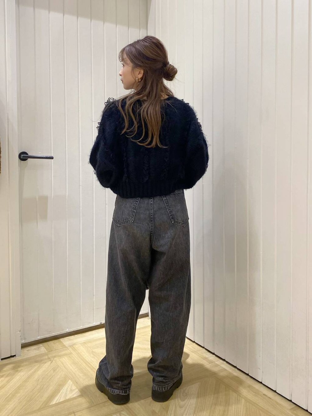 ブラック系のデニムパンツ、ブラック系のニット/セーター、ブラック系のショルダーバッグを着用したレディースの秋コーディネートの2枚目の写真