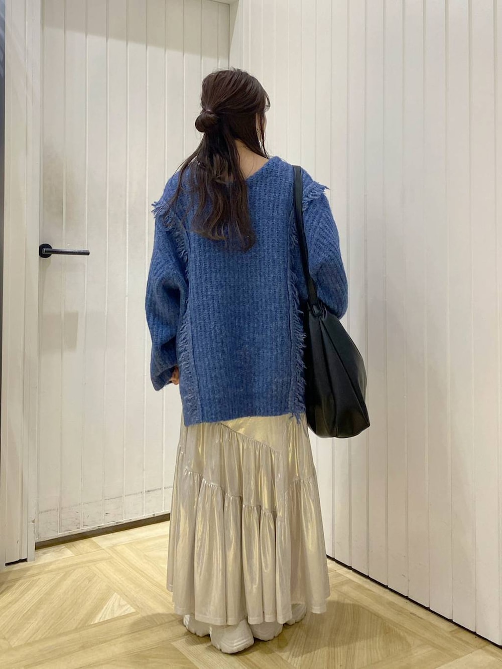 ブルー系のニット/セーター、ホワイト系のタンクトップ、ホワイト系のスニーカーを着用したレディースの秋コーディネートの4枚目の写真