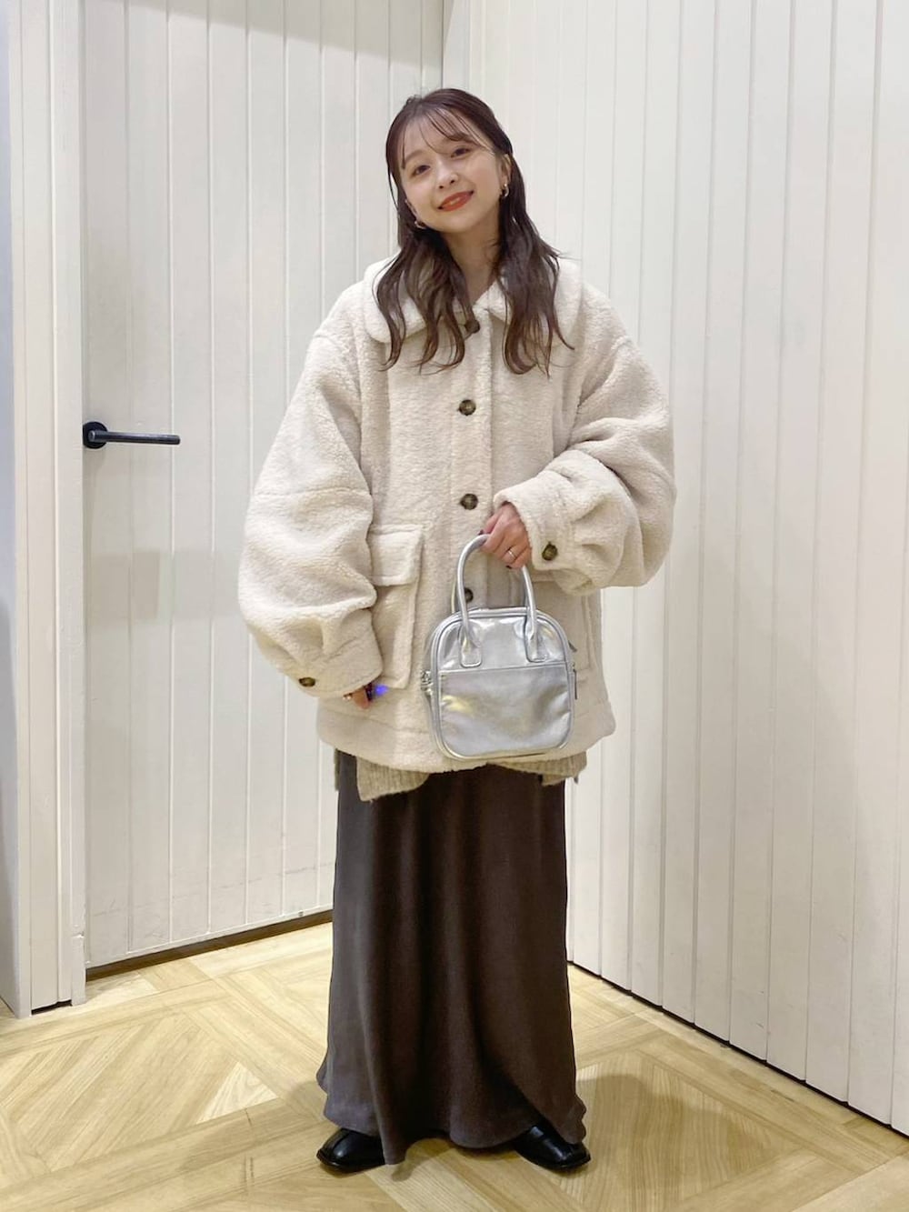 ホワイト系のブルゾン、ブラック系のパンプス、グレー系のスカートを着用したレディースの冬コーディネートの2枚目の写真