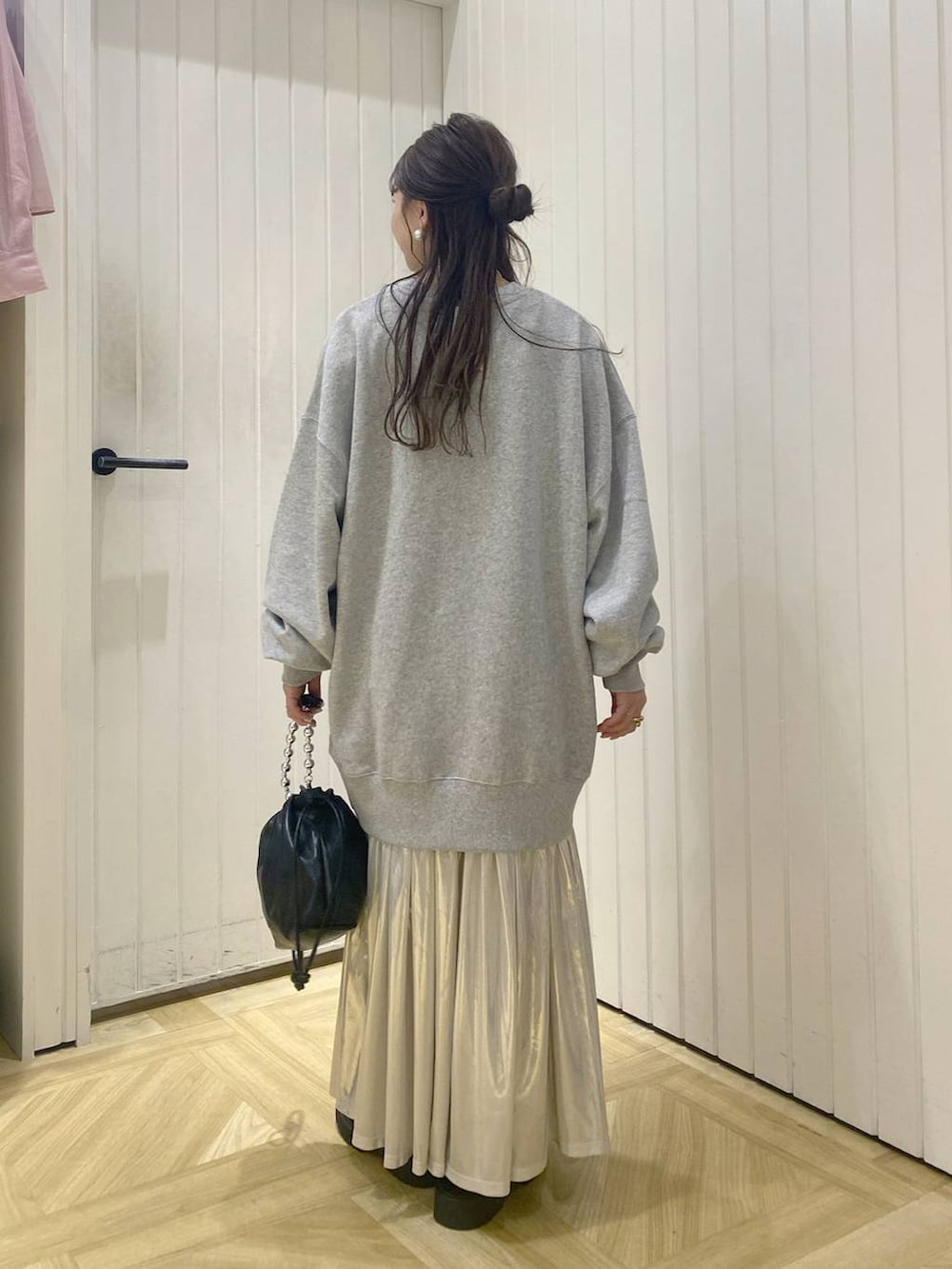 グレー系のスウェット、ホワイト系のスカート、ブラック系のショルダーバッグを着用したレディースの秋コーディネートの3枚目の写真