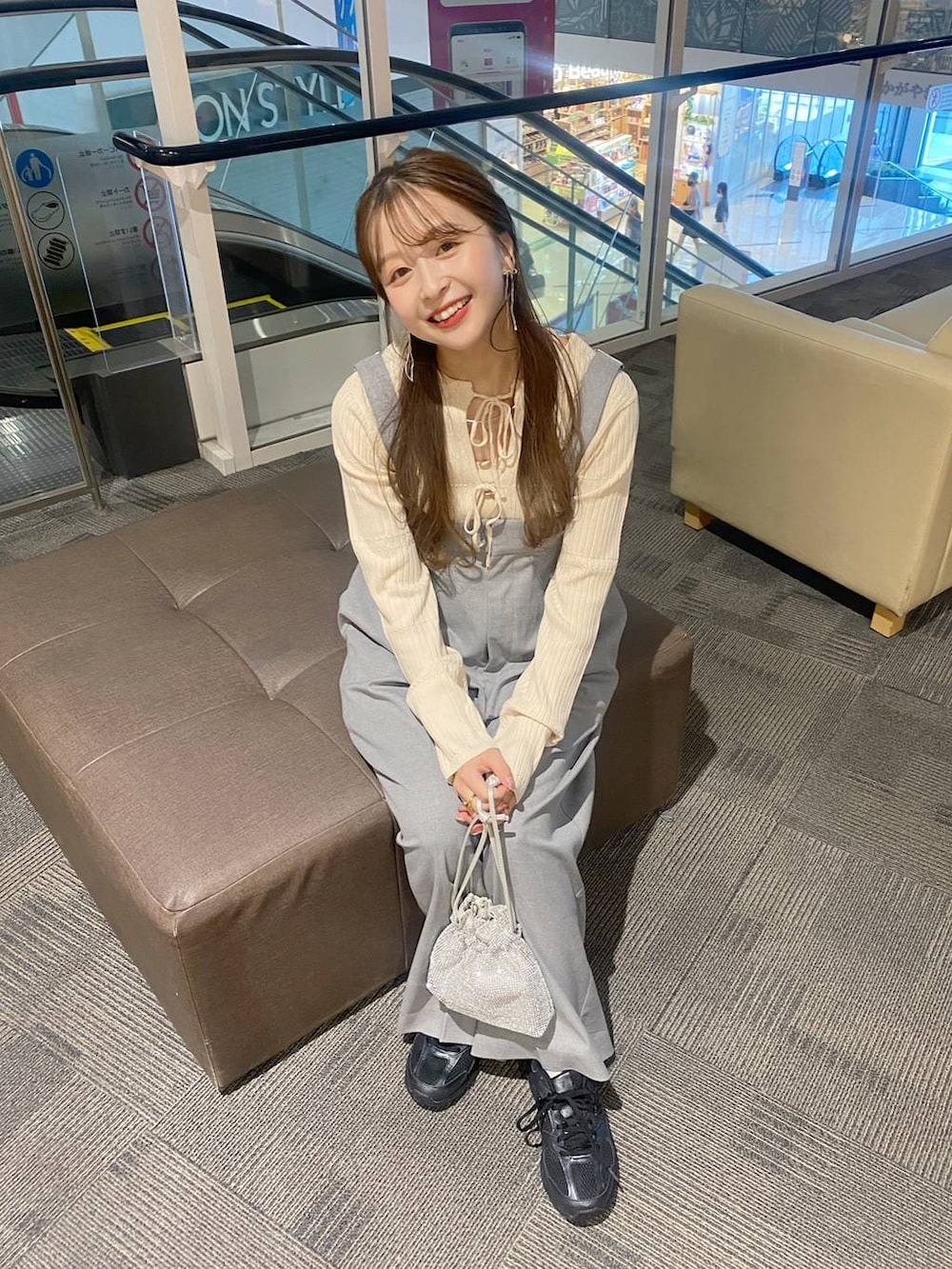 グレー系のサロペット/オーバーオール、シルバー系のショルダーバッグ、ベージュ系のニット/セーターを着用したレディースの秋コーディネートの2枚目の写真