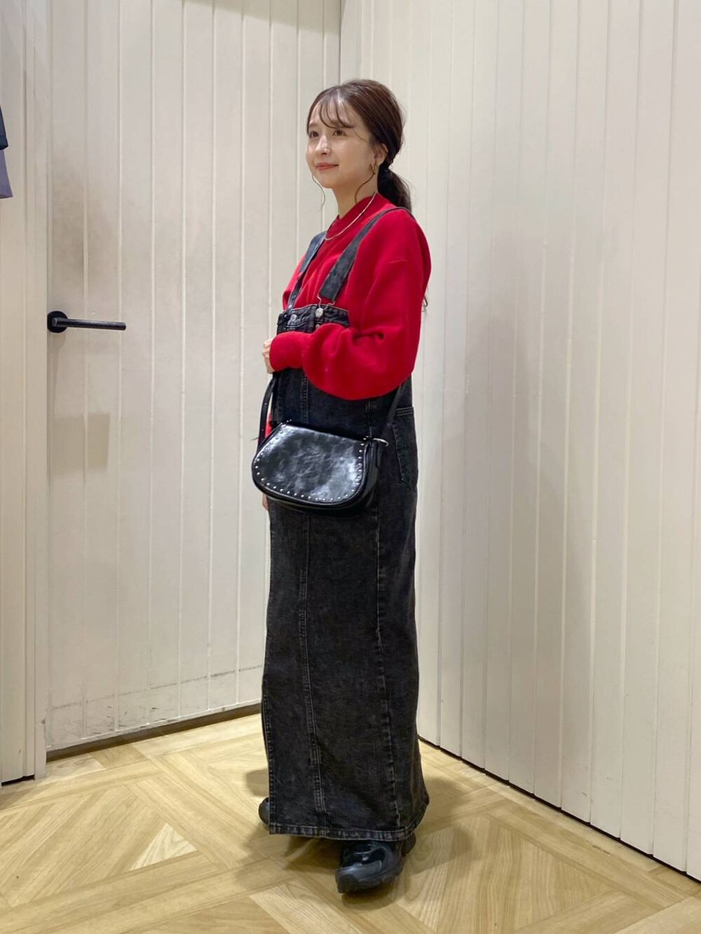 ブラック系のその他シューズ、ブラック系のジャンパースカート、レッド系のニット/セーターを着用したレディースの秋コーディネートの3枚目の写真