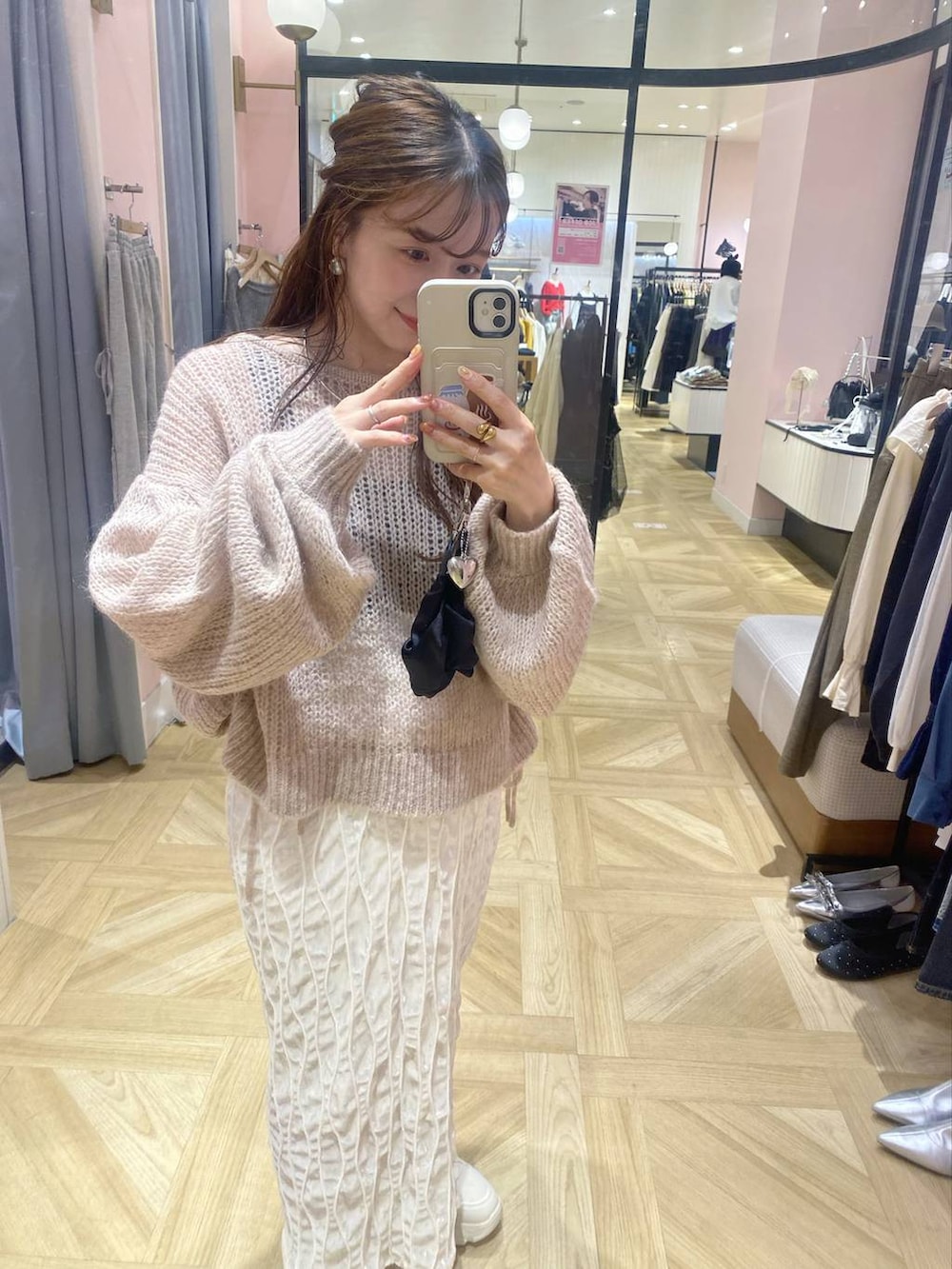 シルバー系のボストンバッグ、ホワイト系のスニーカー、ホワイト系のスカートを着用したレディースの秋コーディネートの3枚目の写真