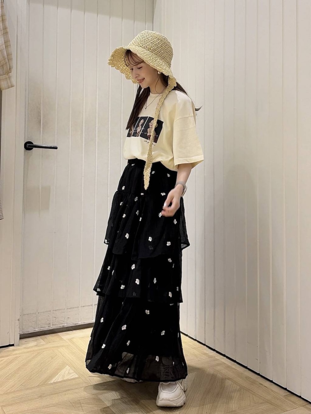 ベージュ系のTシャツ/カットソー、ブラック系のスカート、ホワイト系のスニーカーを着用したレディースの夏コーディネートの2枚目の写真