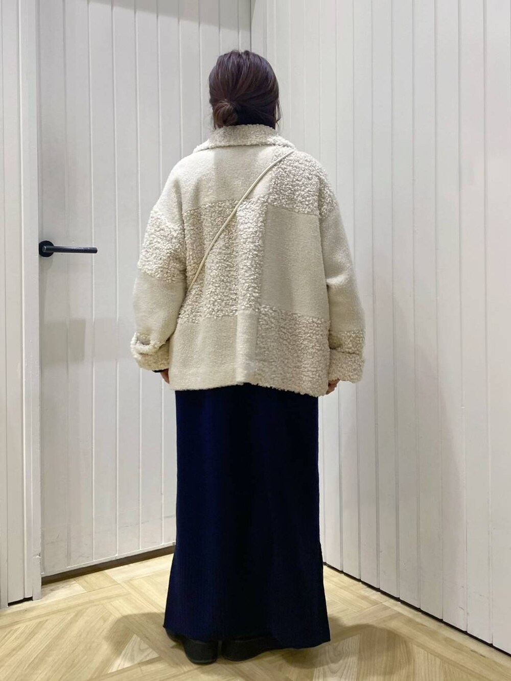 ブラック系のブーツ、ブルー系のワンピース、ホワイト系のショルダーバッグを着用したレディースの冬コーディネートの3枚目の写真