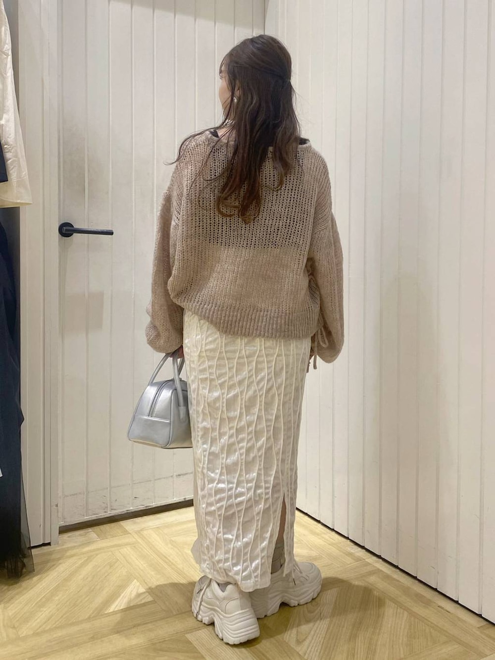 シルバー系のボストンバッグ、ホワイト系のスニーカー、ホワイト系のスカートを着用したレディースの秋コーディネートの2枚目の写真