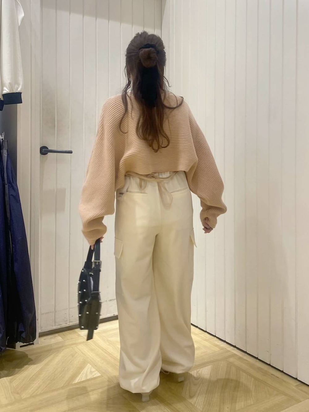 ピンク系のニット/セーター、ホワイト系のスラックス、ホワイト系のブーツを着用したレディースの秋コーディネートの3枚目の写真