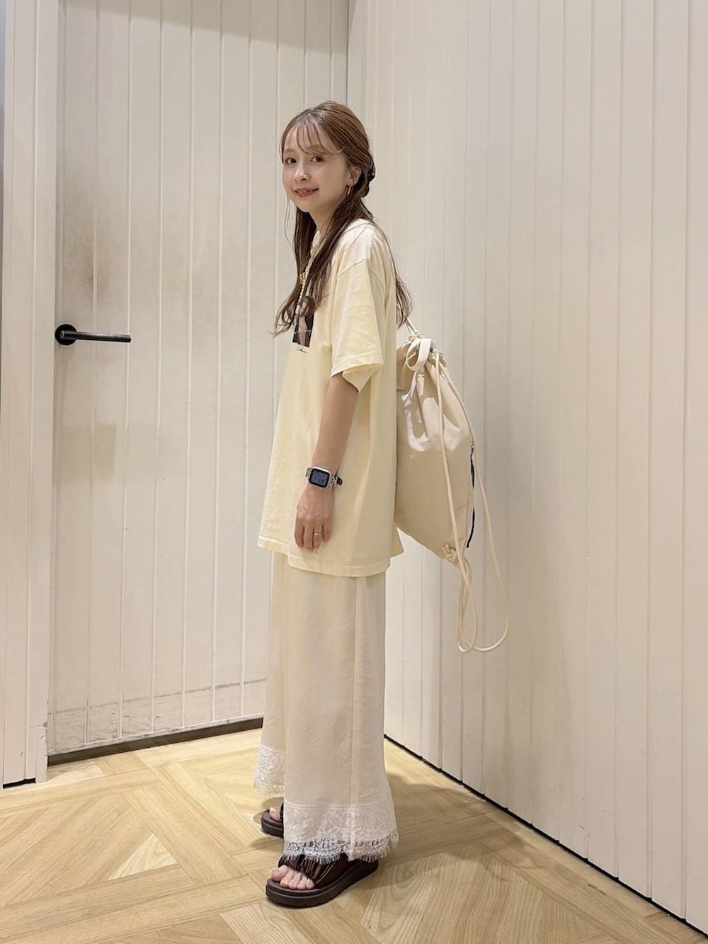 ブラウン系のサンダル、ベージュ系のTシャツ/カットソー、ホワイト系のバックパック/リュックを着用したレディースの夏コーディネートの2枚目の写真