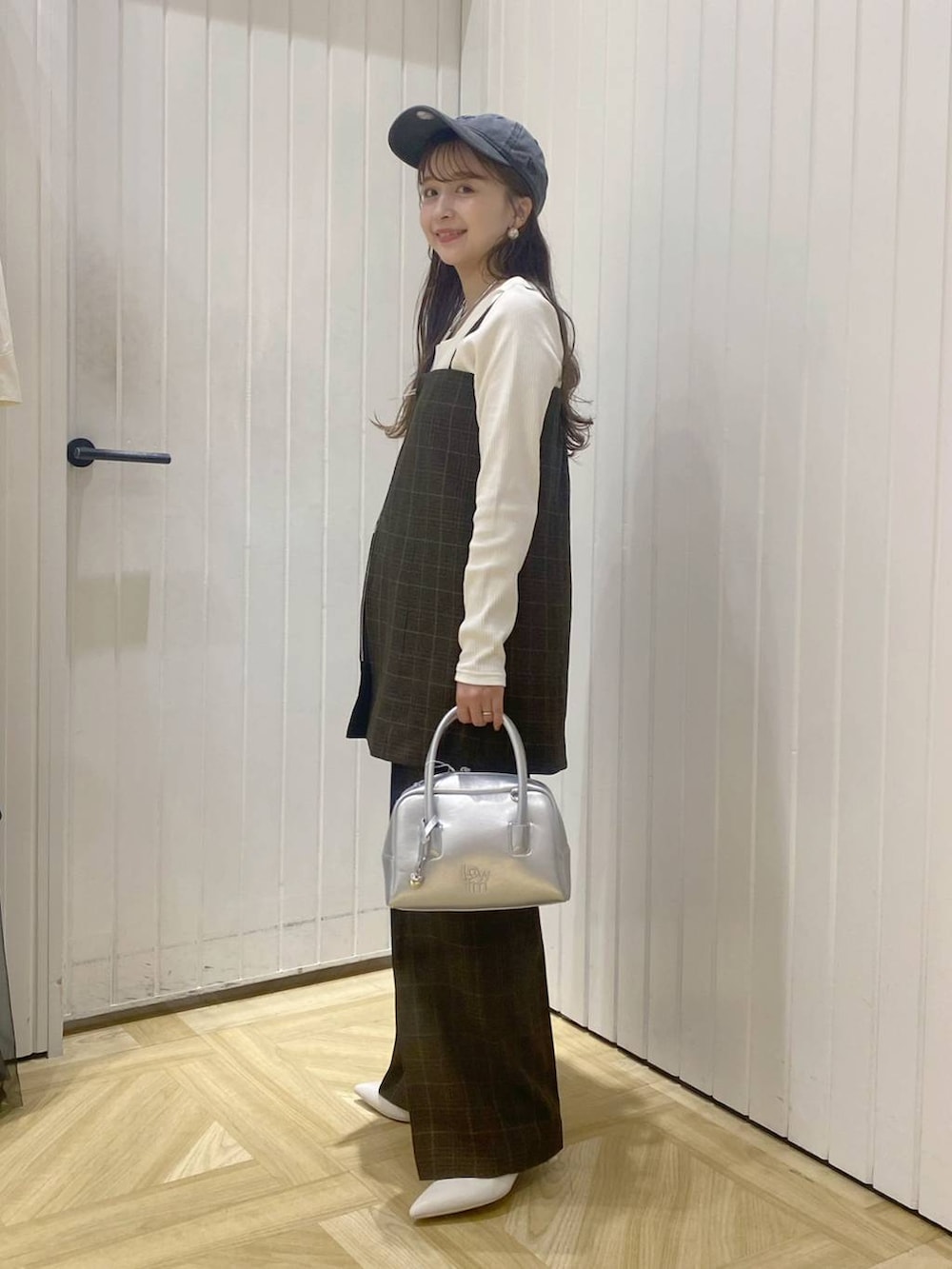 ブラウン系のスラックス、ブラウン系のベスト、シルバー系のボストンバッグを着用したレディースの秋コーディネートの2枚目の写真