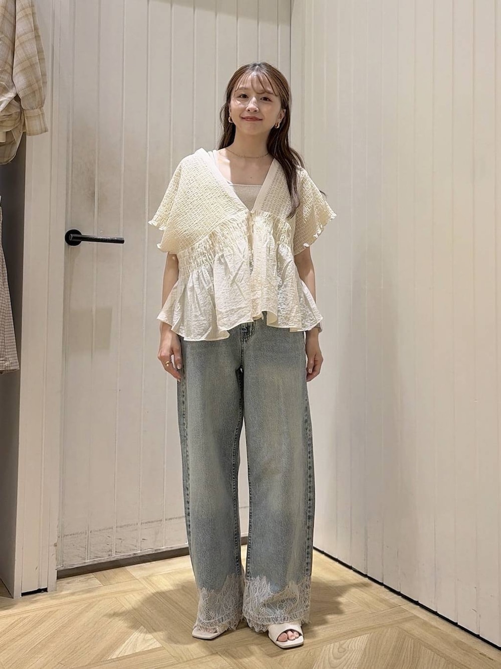 ゴールド系のタンクトップ、ブルー系のデニムパンツ、ホワイト系のサンダルを着用したレディースの夏コーディネートの3枚目の写真