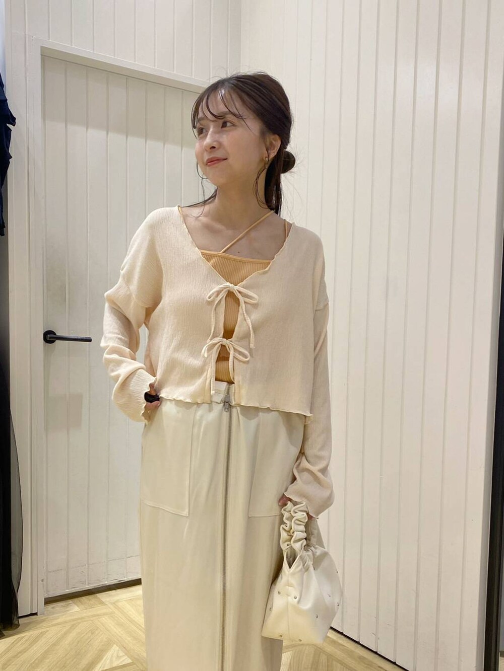 ベージュ系のハンドバッグ、ホワイト系のサンダル、オレンジ系のキャミソールを着用したレディースの夏コーディネートの5枚目の写真