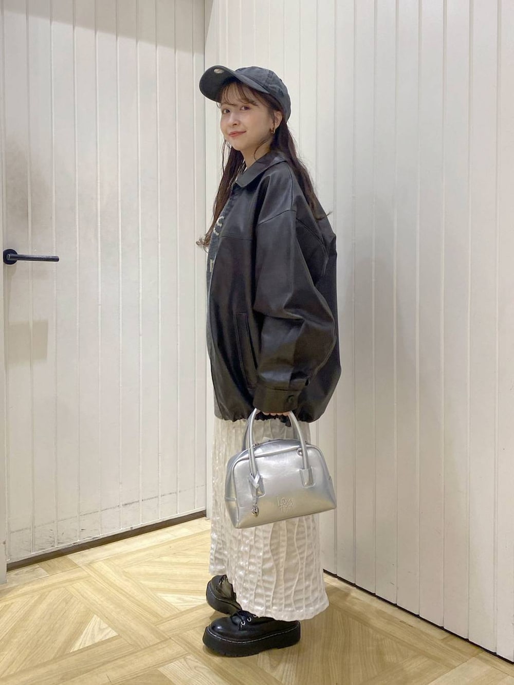 ブラウン系のブルゾン、シルバー系のボストンバッグ、グレー系のニット/セーターを着用したレディースの秋コーディネートの2枚目の写真