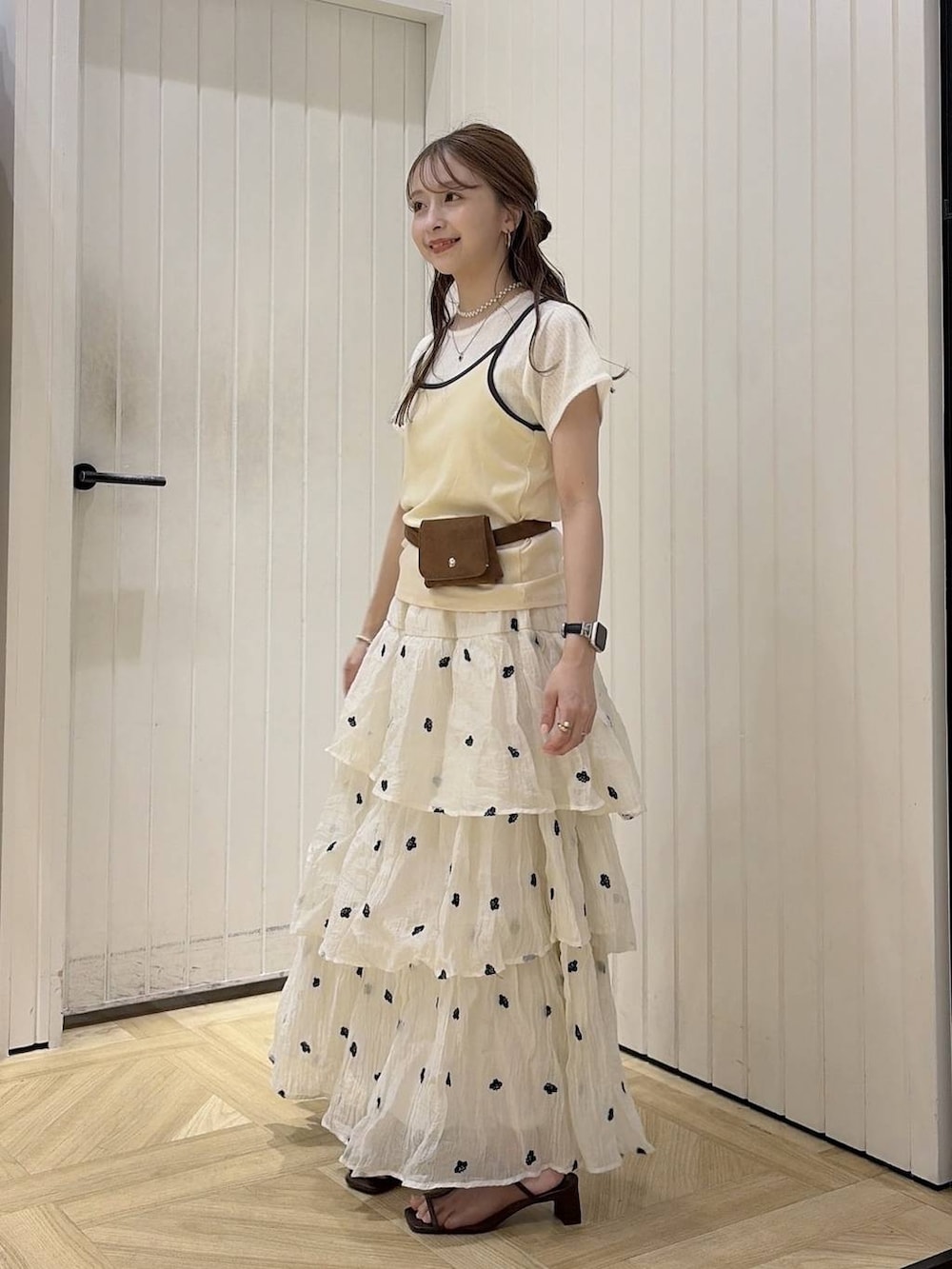 ベージュ系のTシャツ/カットソー、ブラウン系のサンダル、ホワイト系のスカートを着用したレディースの夏コーディネートの2枚目の写真