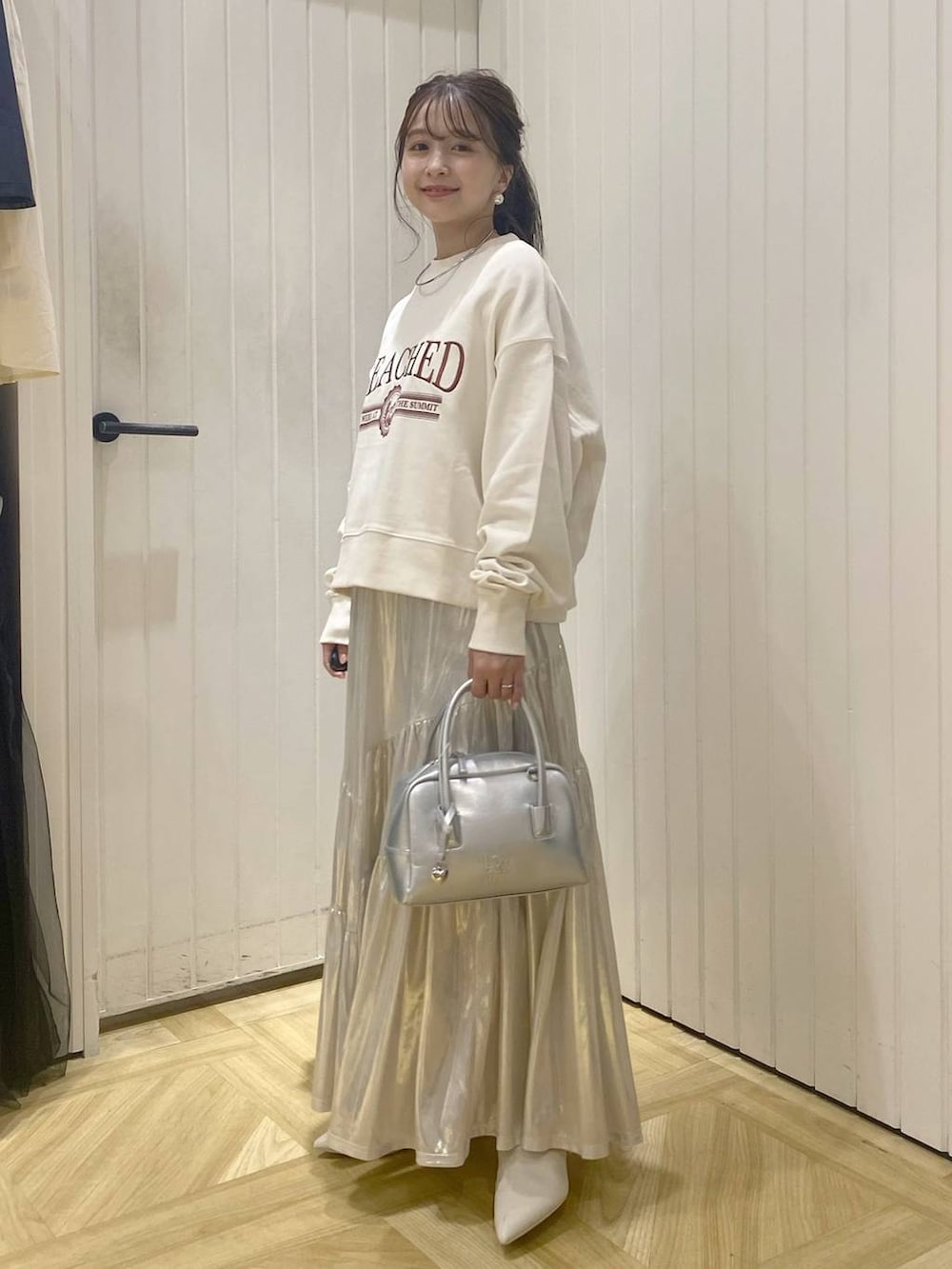 ホワイト系のスウェット、シルバー系のボストンバッグ、ホワイト系のブーツを着用したレディースの秋コーディネートの3枚目の写真