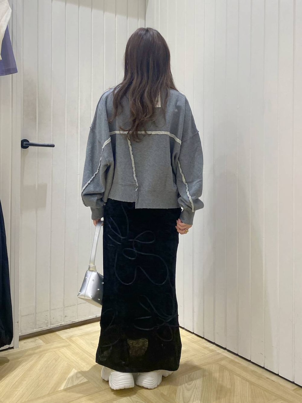 グレー系のスウェット、ブラック系のスカート、ホワイト系のスニーカーを着用したレディースの秋コーディネートの3枚目の写真