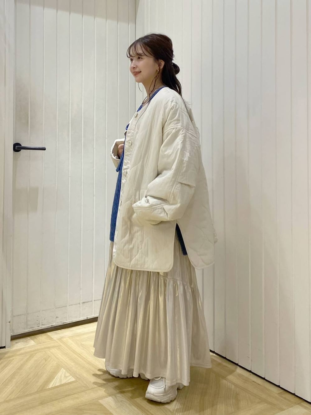 ホワイト系のブルゾン、ブルー系のニット/セーター、ホワイト系のスニーカーを着用したレディースの秋コーディネートの2枚目の写真