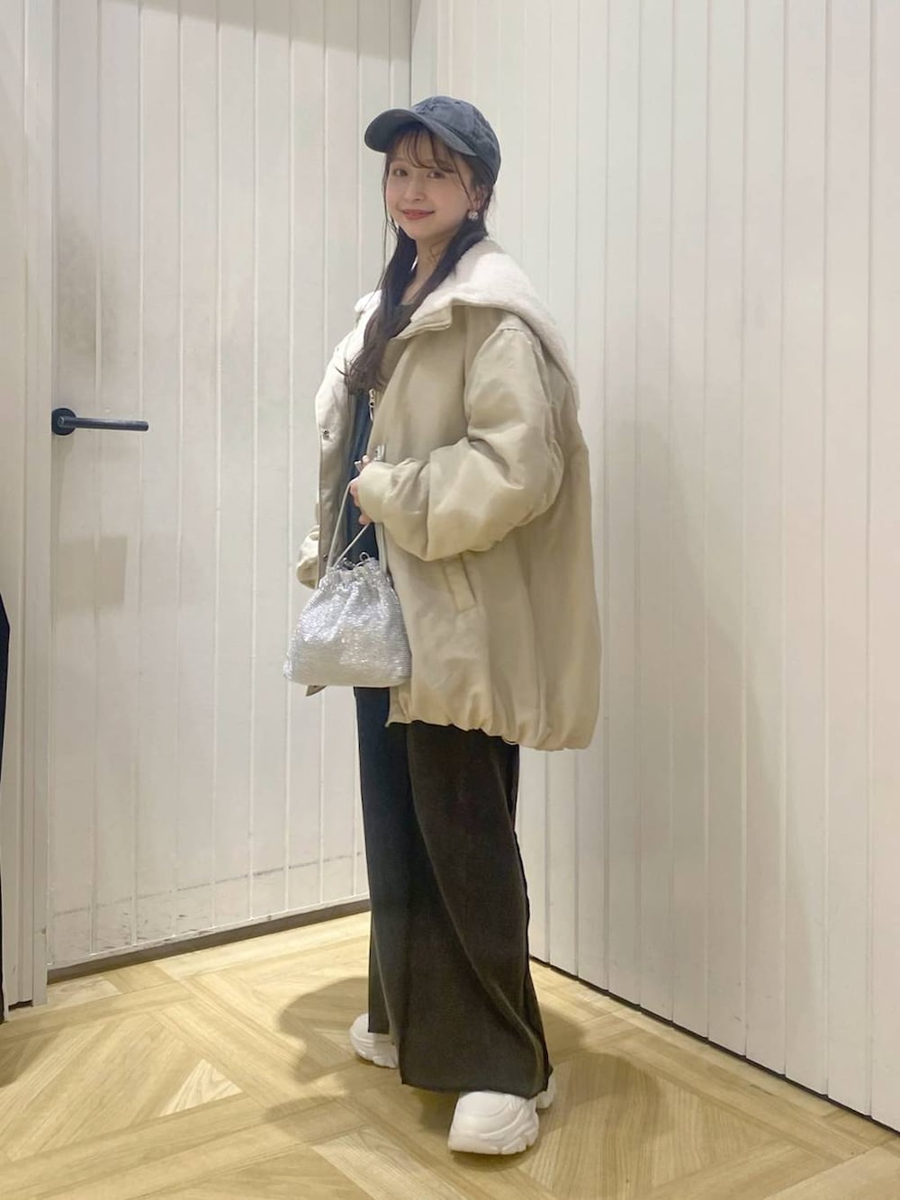 ホワイト系のブルゾン、ホワイト系のスニーカー、シルバー系のショルダーバッグを着用したレディースの秋コーディネートの2枚目の写真
