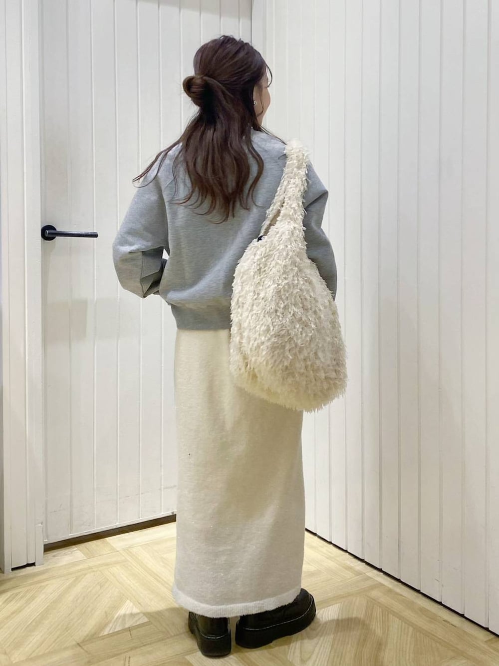 ホワイト系のトートバッグ、グレー系のスウェット、ゴールド系のネックレスを着用したレディースの冬コーディネートの3枚目の写真