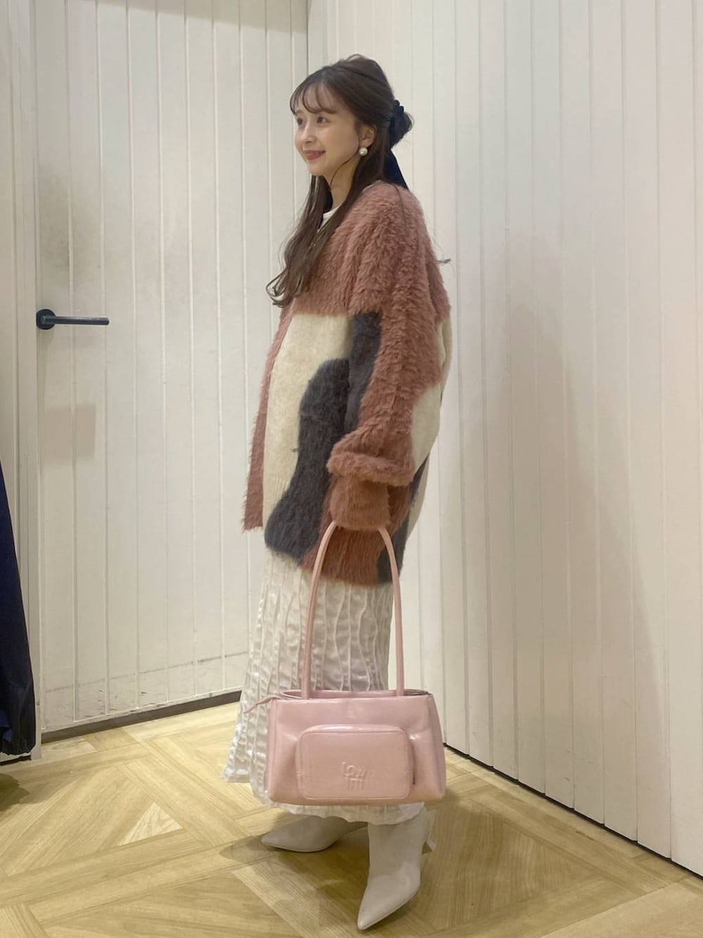 ピンク系のショルダーバッグ、ホワイト系のブーツ、ピンク系のカーディガン/ボレロを着用したレディースの秋コーディネートの2枚目の写真