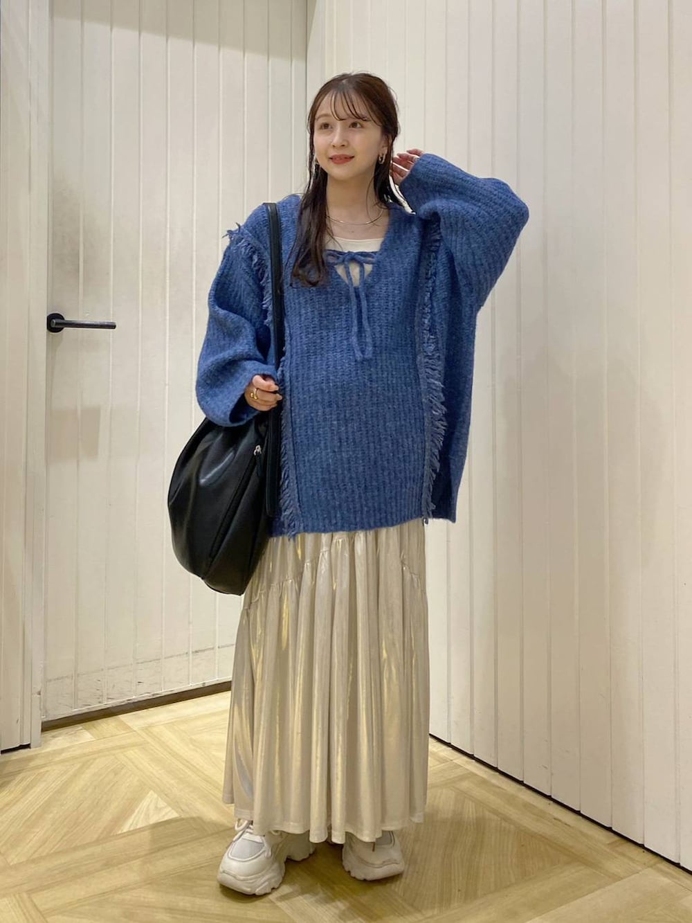 ブルー系のニット/セーター、ホワイト系のタンクトップ、ホワイト系のスニーカーを着用したレディースの秋コーディネートの2枚目の写真