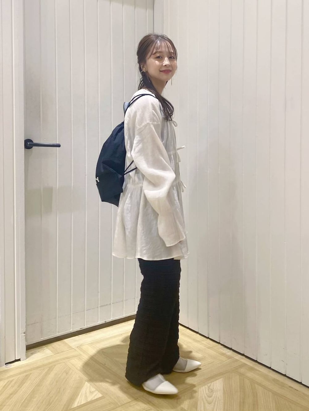 ホワイト系のブーツ、ブラック系のバックパック/リュック、ホワイト系のシャツ/ブラウスを着用したレディースの春コーディネートの3枚目の写真