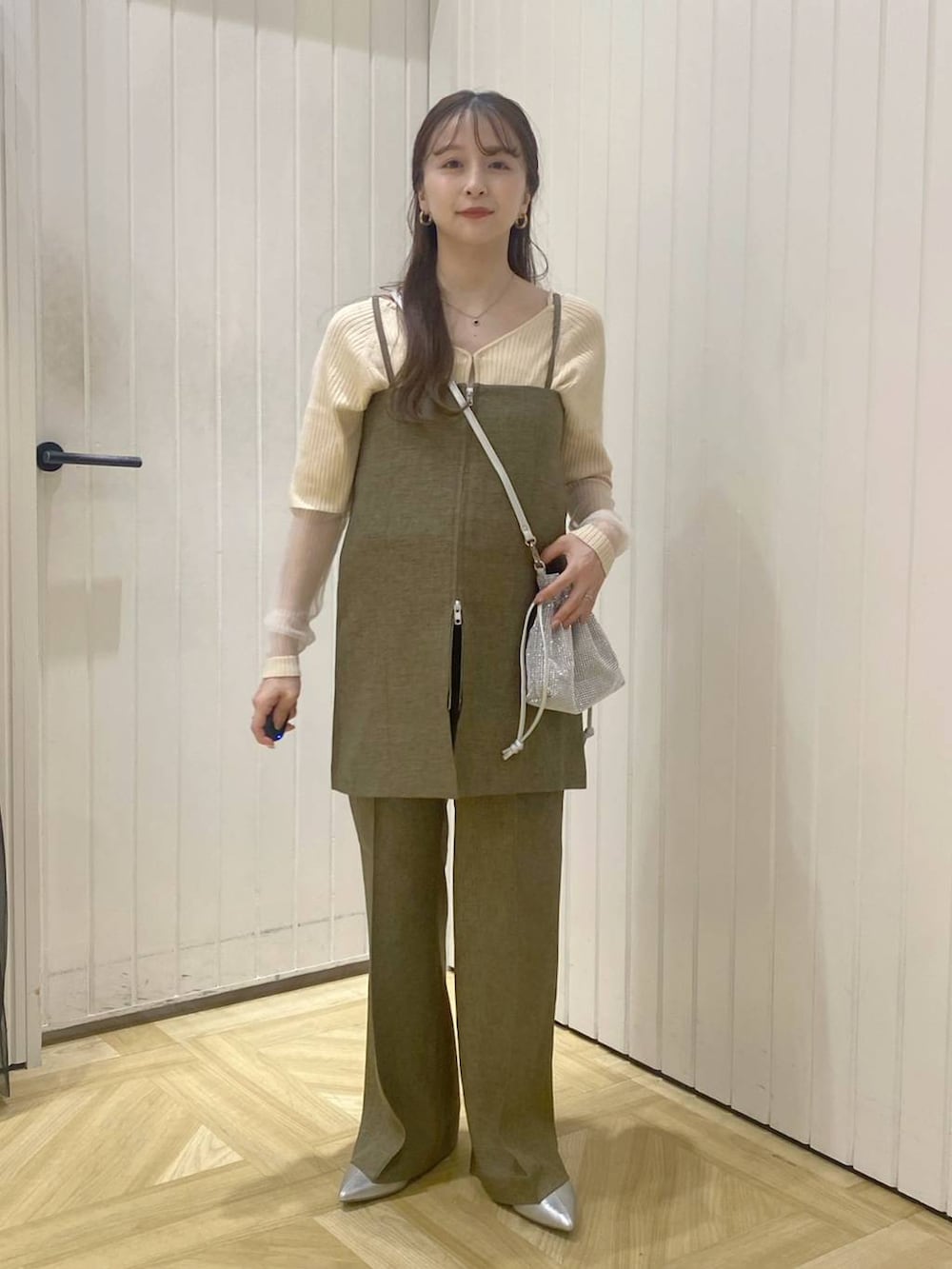 ブラウン系のスラックス、シルバー系のショルダーバッグ、シルバー系のブーツを着用したレディースの秋コーディネートの2枚目の写真