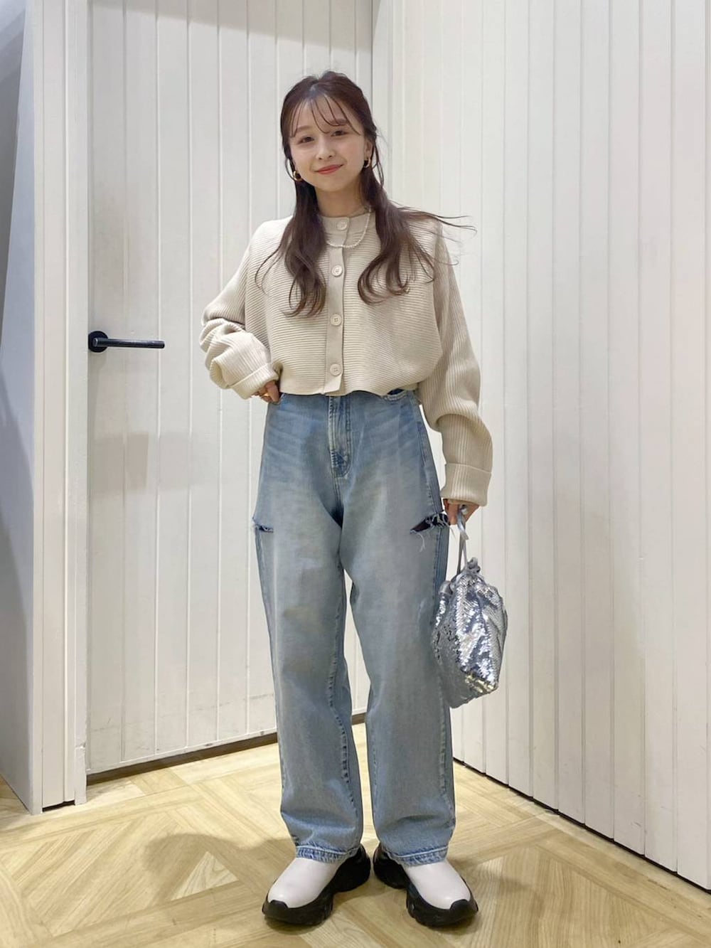 ブルー系のデニムパンツ、シルバー系のハンドバッグ、ホワイト系のブーツを着用したレディースの冬コーディネートの2枚目の写真