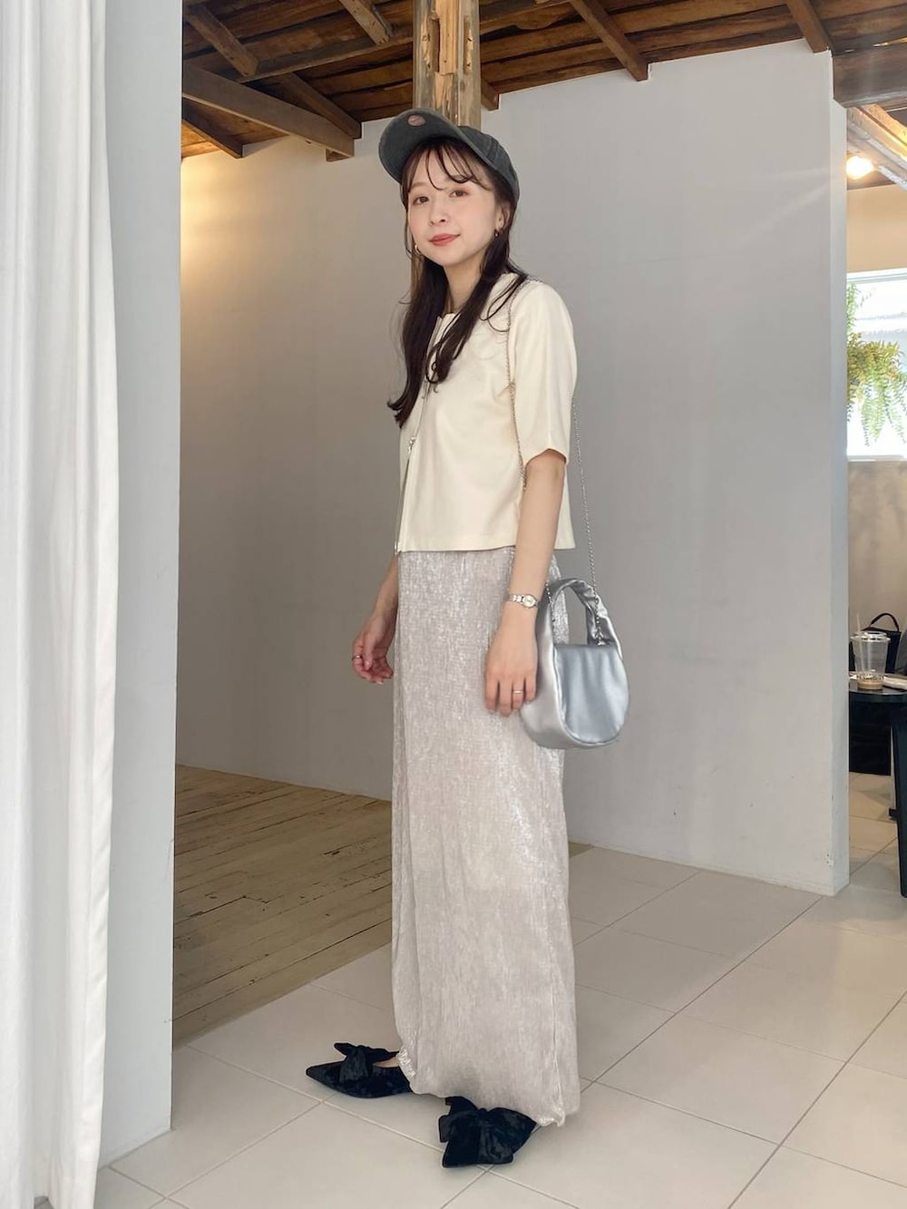 ブラック系のパンプス、シルバー系のショルダーバッグ、ホワイト系のスカートを着用したレディースの春コーディネートの2枚目の写真