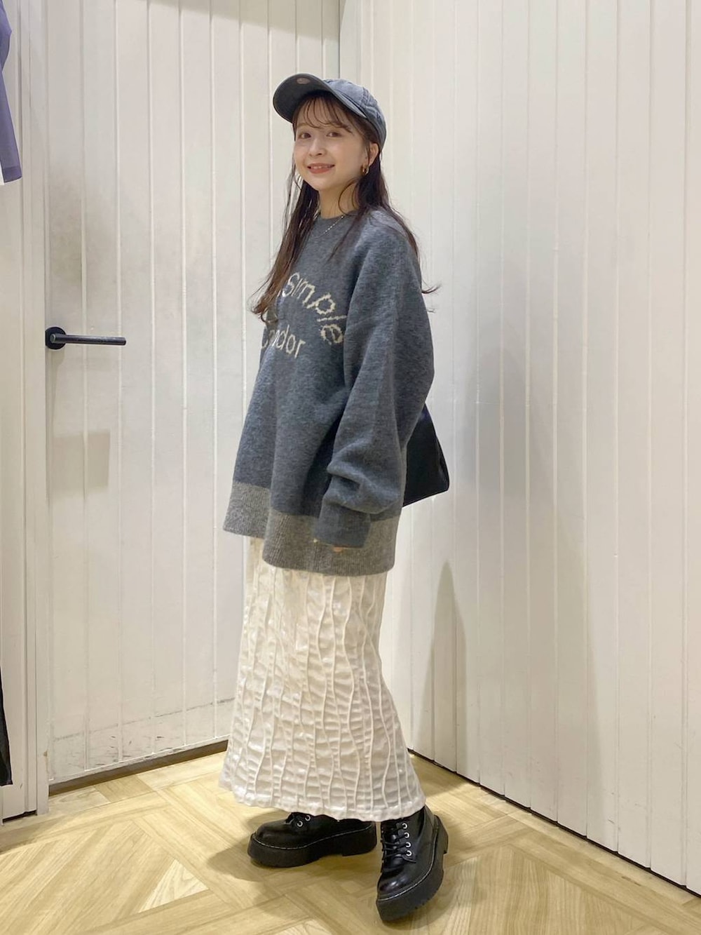 グレー系のニット/セーター、ホワイト系のスカート、ブラック系のショルダーバッグを着用したレディースの秋コーディネートの3枚目の写真