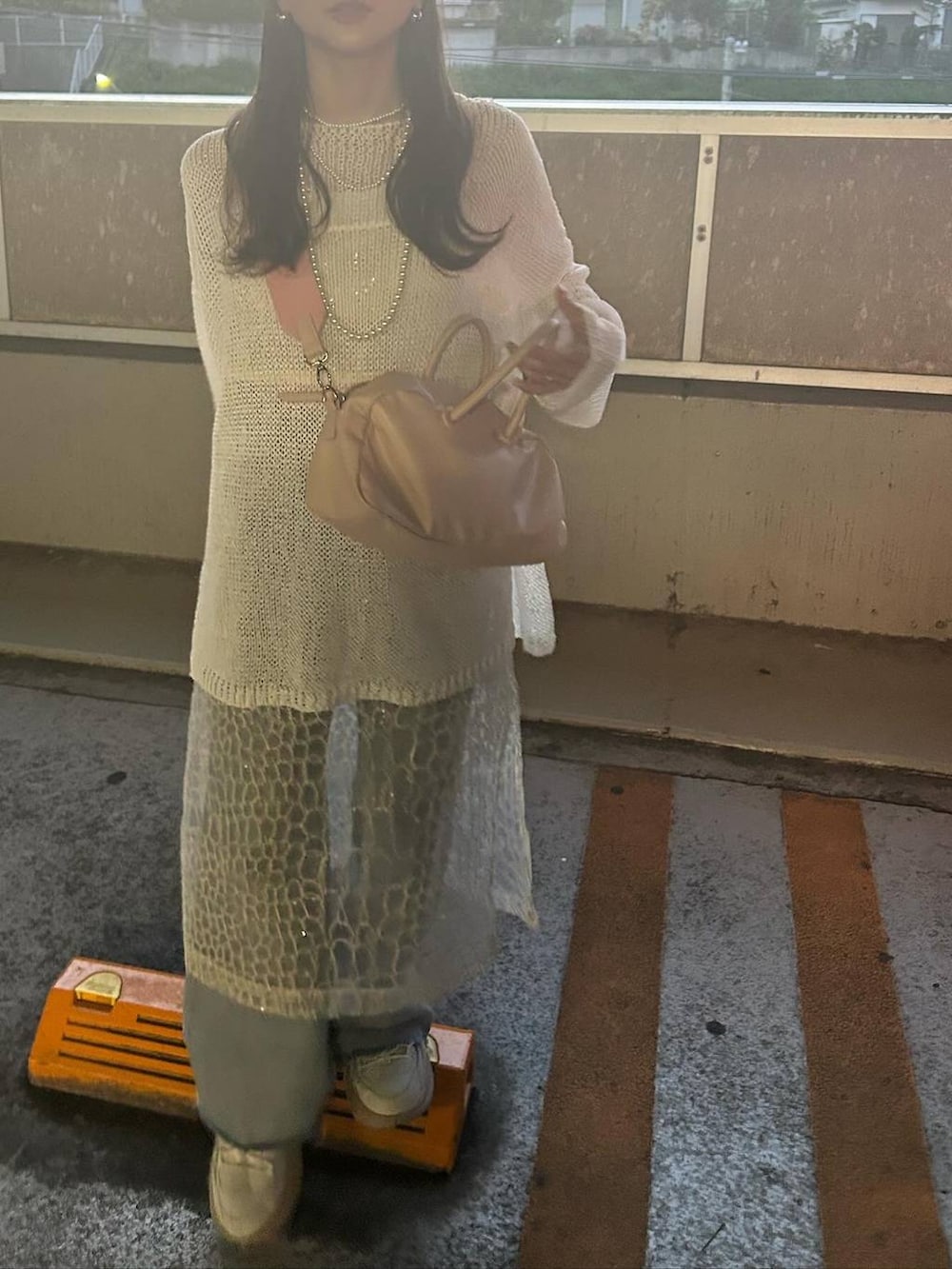 ホワイト系のワンピース、ブルー系のデニムパンツ、ホワイト系のニット/セーターを着用したレディースの春コーディネートの2枚目の写真