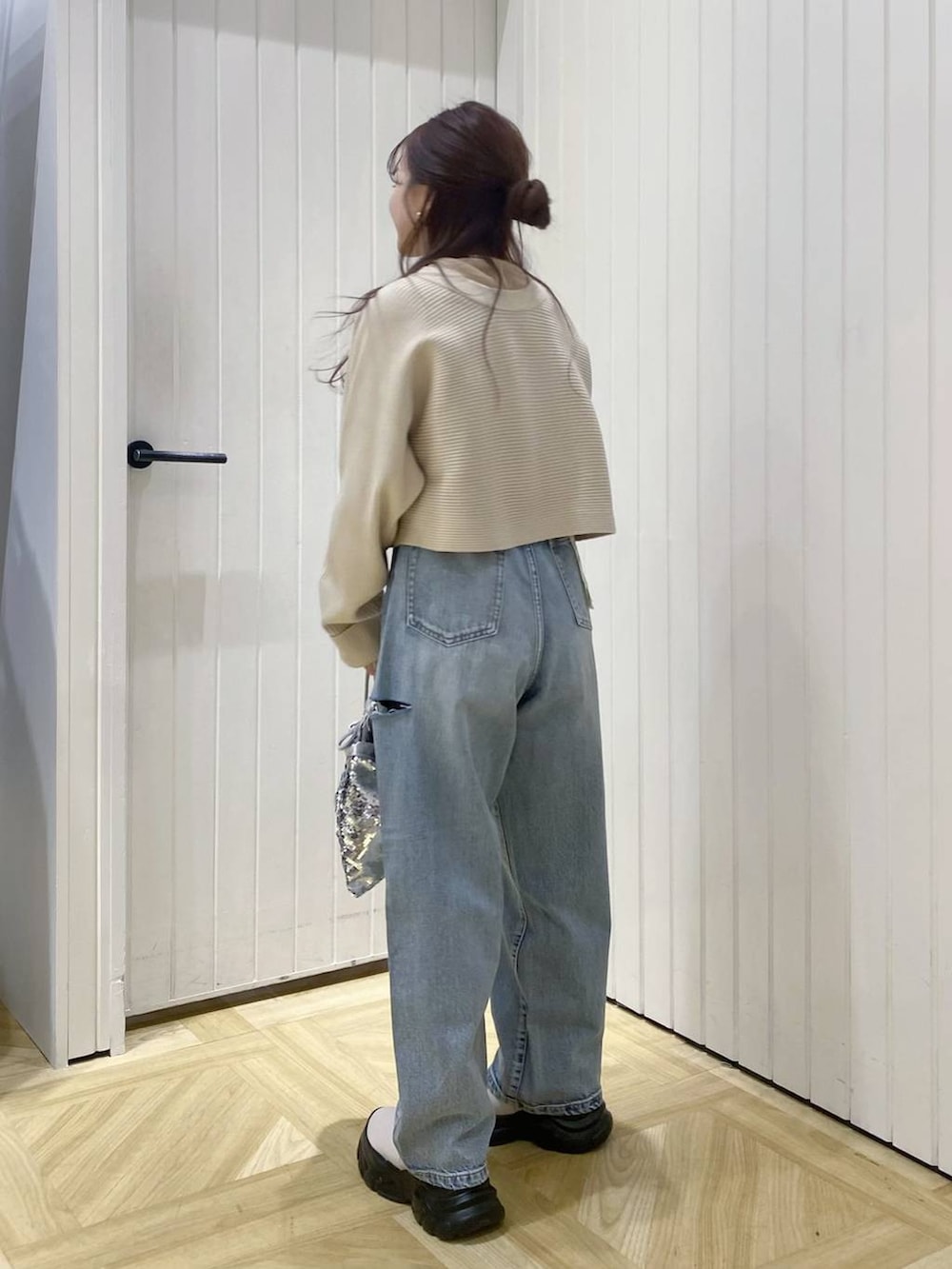 ブルー系のデニムパンツ、シルバー系のハンドバッグ、ホワイト系のブーツを着用したレディースの冬コーディネートの4枚目の写真