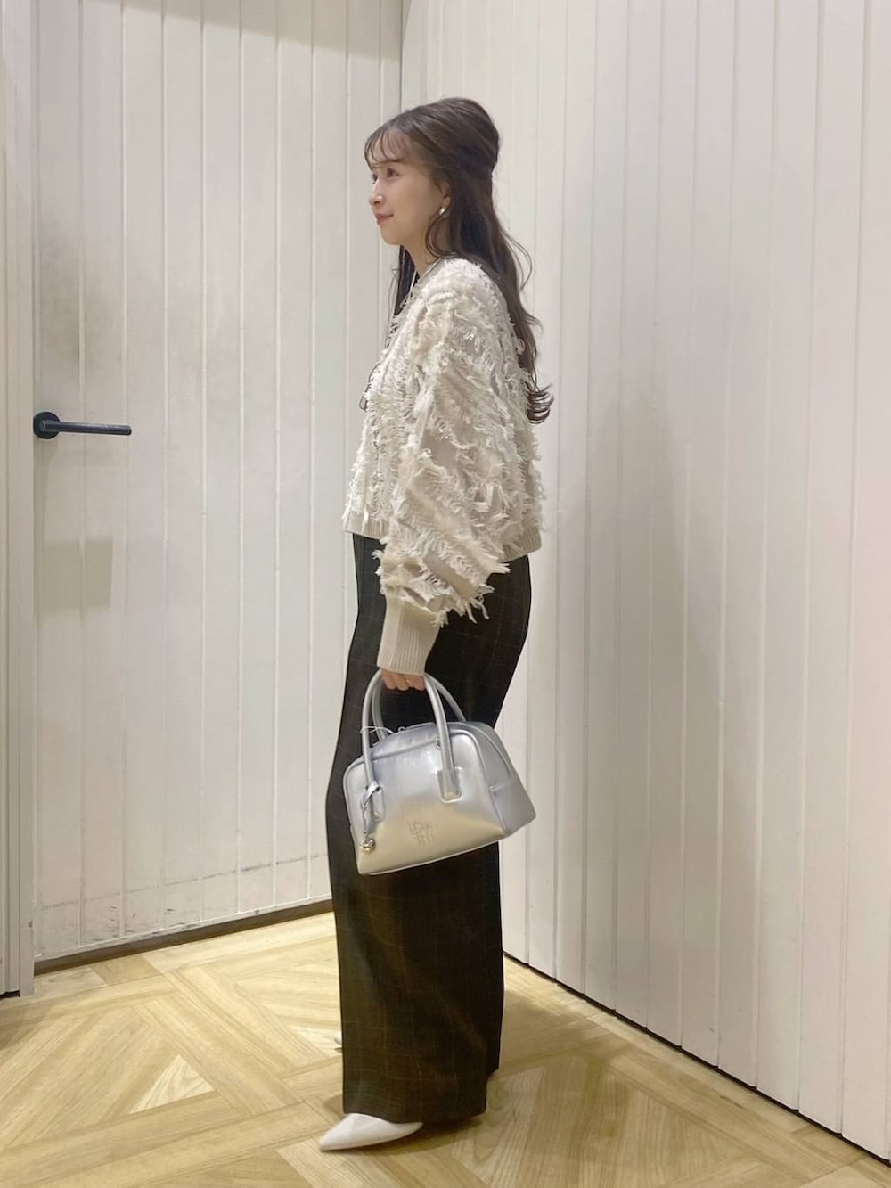 ブラウン系のスラックス、シルバー系のボストンバッグ、ホワイト系のブーツを着用したレディースの秋コーディネートの3枚目の写真