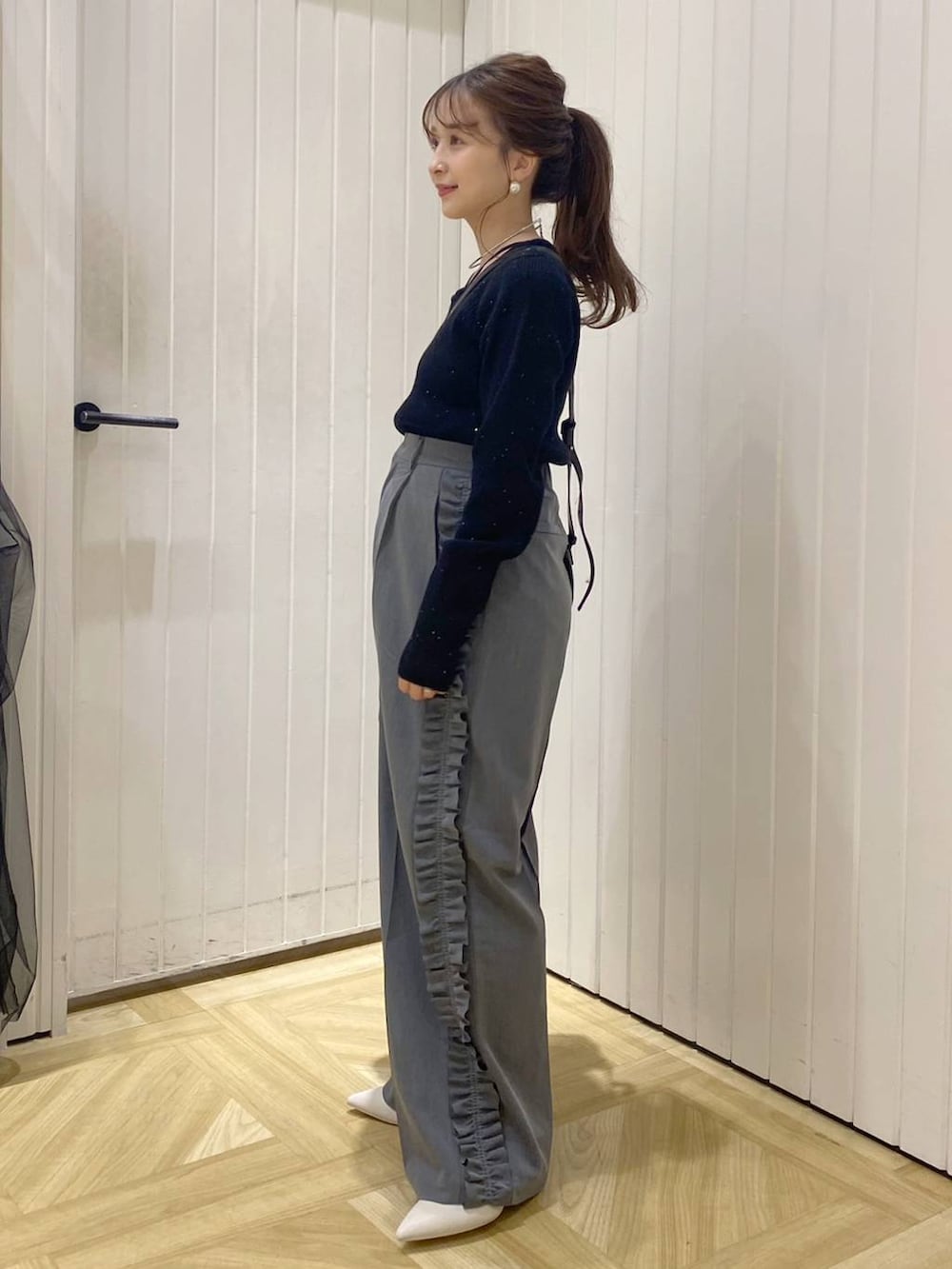 ブラック系のショルダーバッグ、ホワイト系のブーツ、グレー系のその他パンツを着用したレディースの秋コーディネートの2枚目の写真