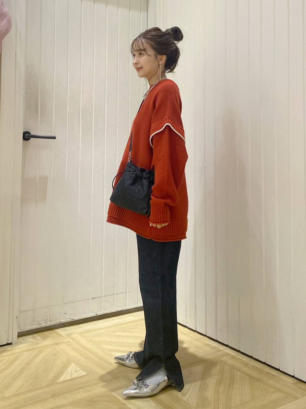 レッド系のニット/セーター、ブルー系のデニムパンツ、ブラック系のショルダーバッグを着用したレディースの秋コーディネートの2枚目の写真