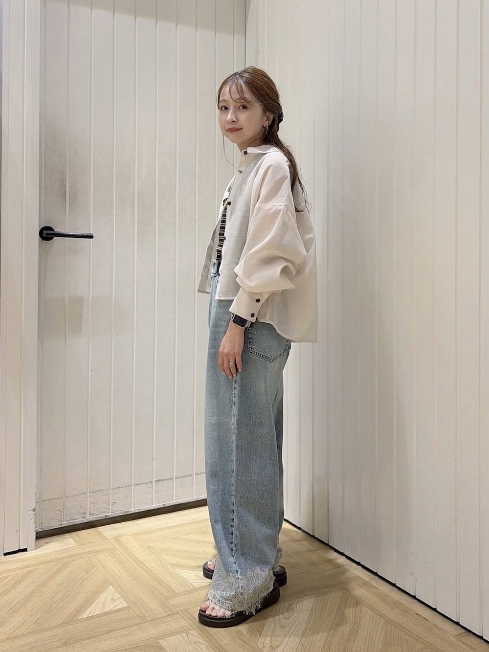 ブルー系のデニムパンツ、ホワイト系のシャツ/ブラウス、ホワイト系のサンダルを着用したレディースの夏コーディネートの2枚目の写真