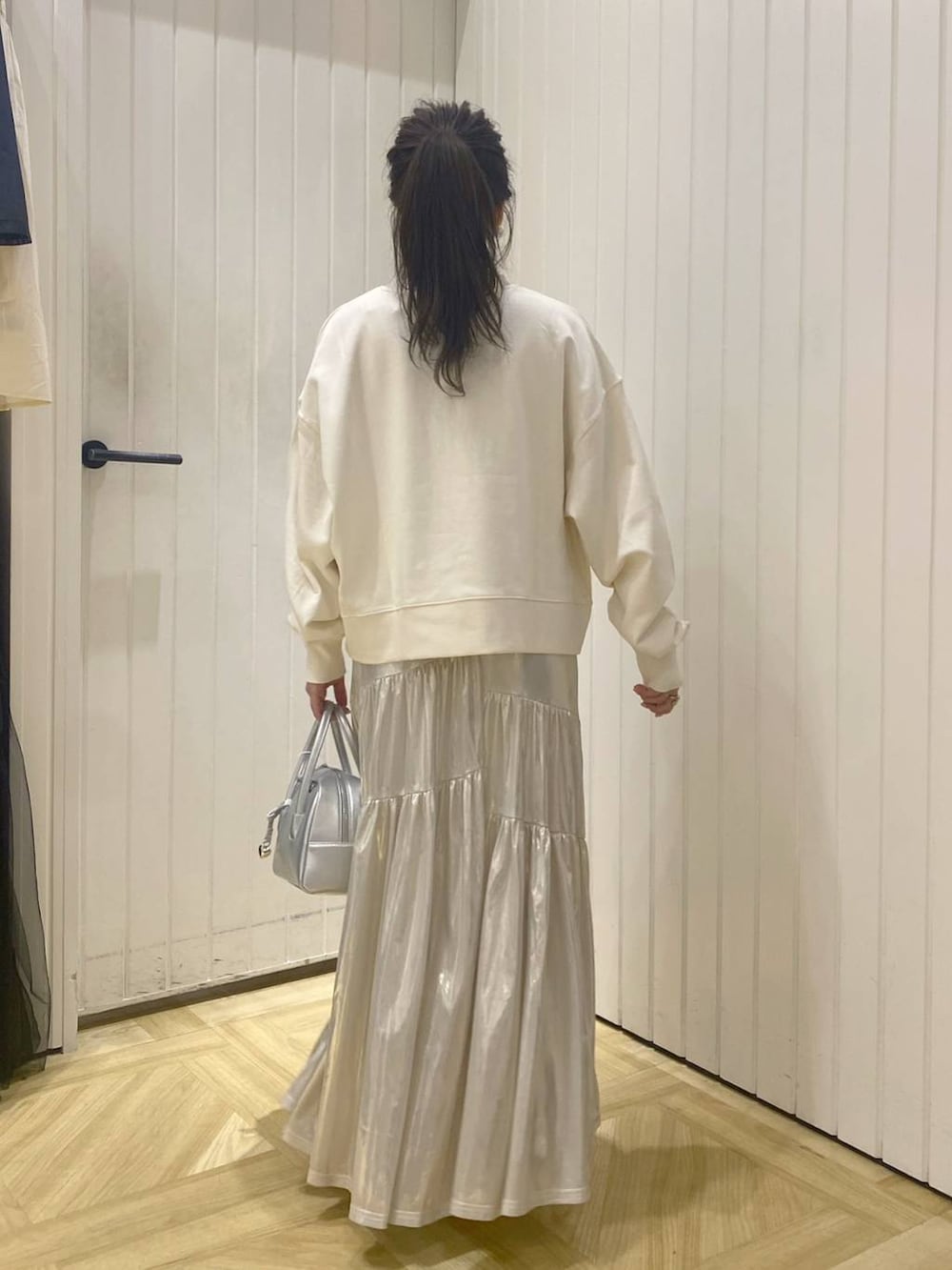 ホワイト系のスウェット、シルバー系のボストンバッグ、ホワイト系のブーツを着用したレディースの秋コーディネートの4枚目の写真