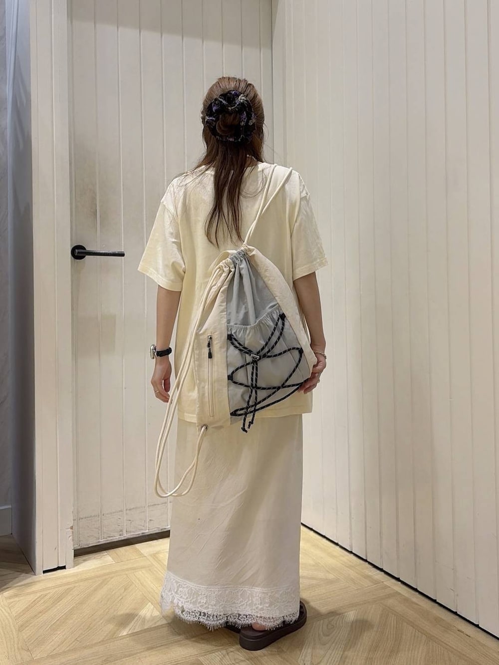 ブラウン系のサンダル、ベージュ系のTシャツ/カットソー、ホワイト系のバックパック/リュックを着用したレディースの夏コーディネートの3枚目の写真