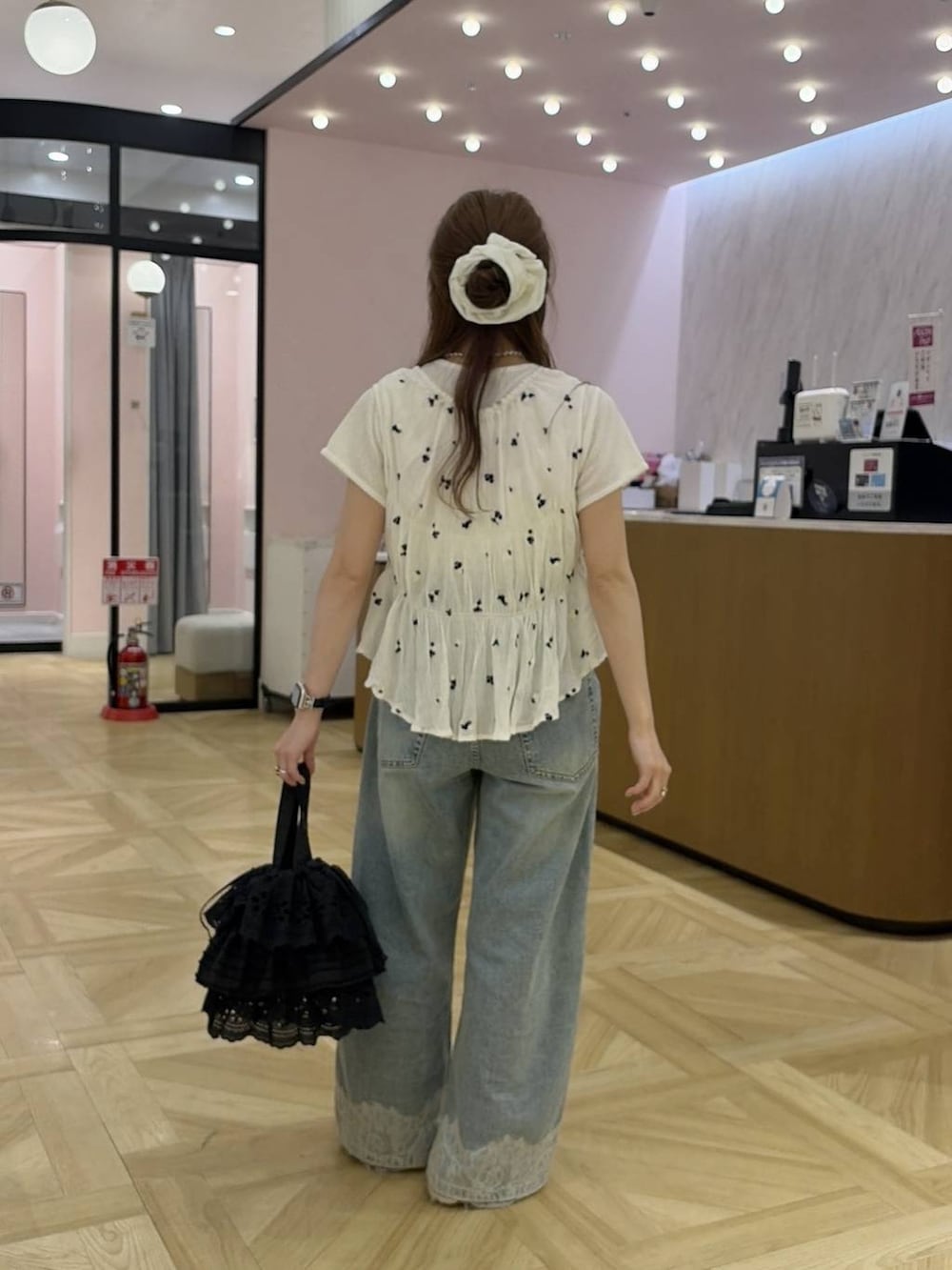 ブルー系のデニムパンツ、ブラック系のハンドバッグ、ホワイト系のシャツ/ブラウスを着用したレディースの夏コーディネートの3枚目の写真