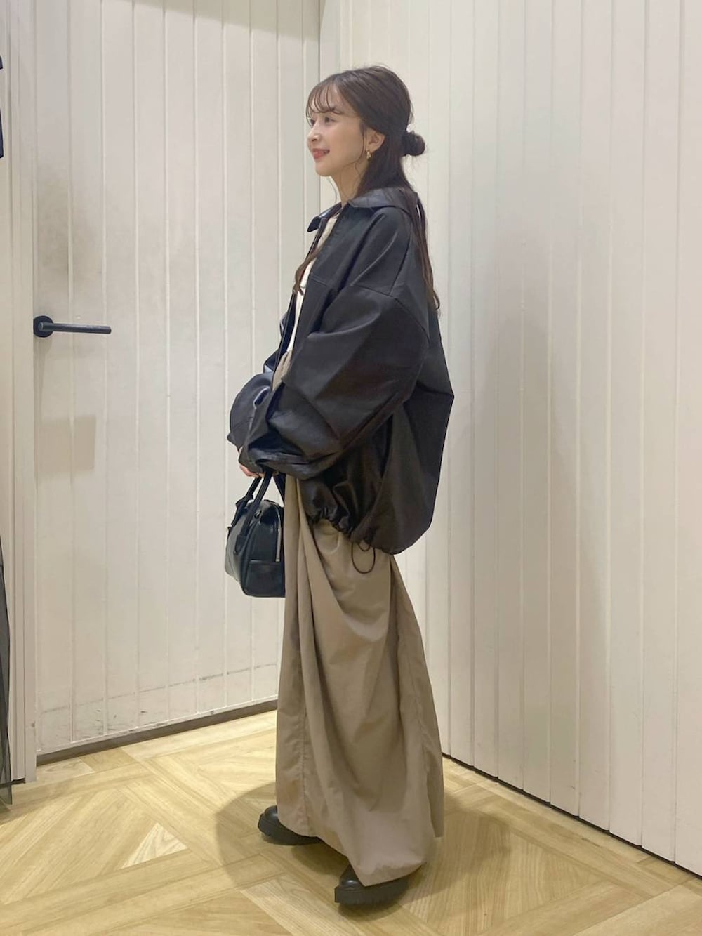 ブラウン系のブルゾン、ブラック系のボストンバッグ、ホワイト系のワンピースを着用したレディースの秋コーディネートの2枚目の写真