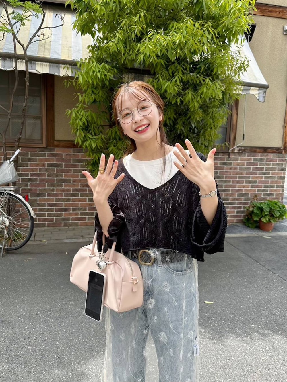 ブラック系のニット/セーター、ブルー系のデニムパンツ、ホワイト系のワンピースを着用したレディースの春コーディネートの2枚目の写真